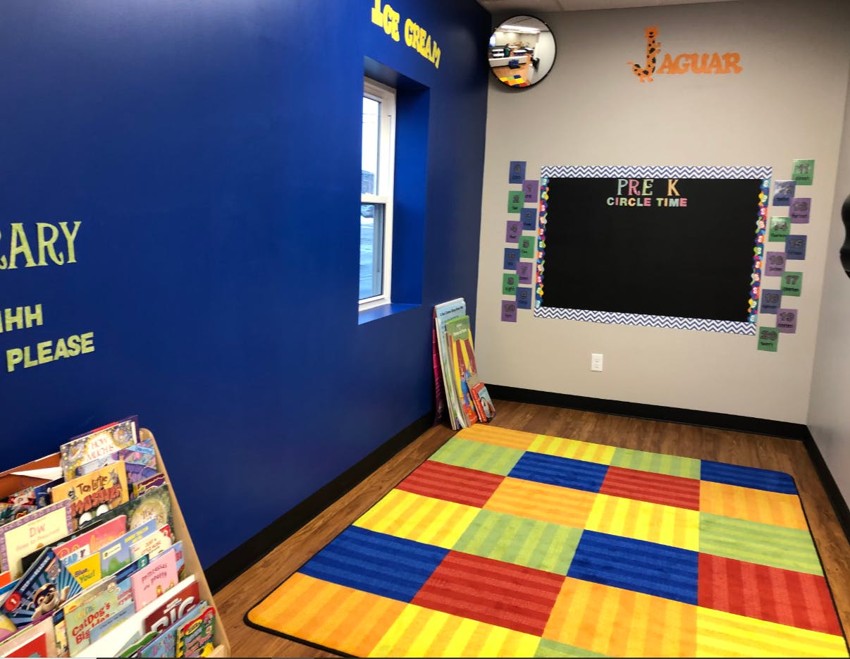 Classroom with colorful rug, chalkboard, and book display