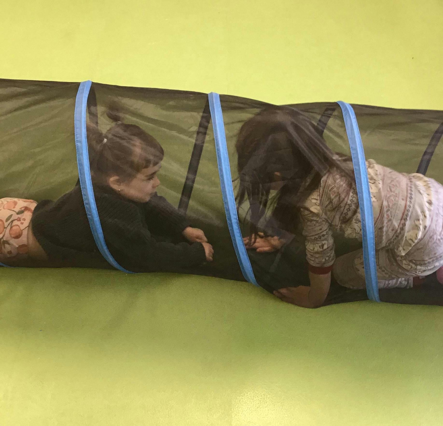 Two children crawling through a play tunnel