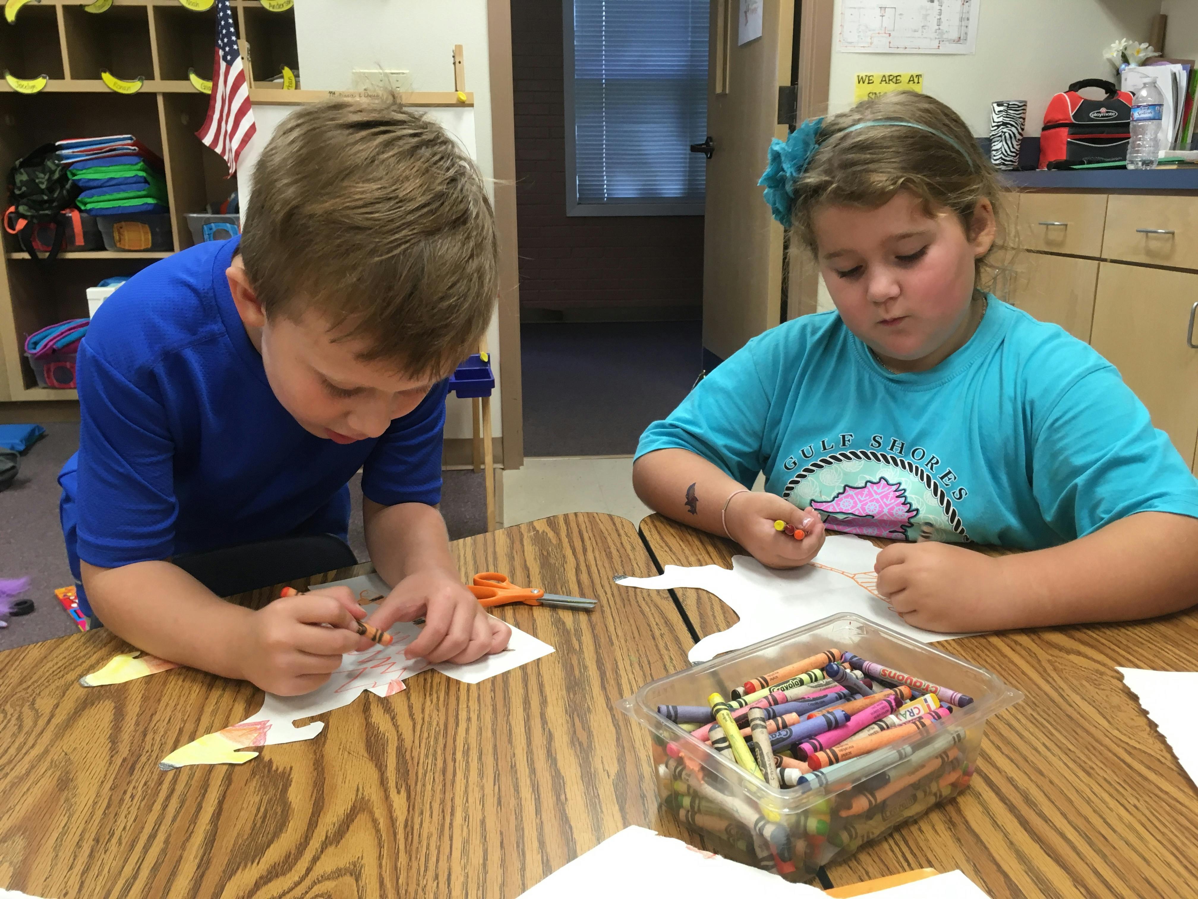 Two children coloring at a table in a classroom