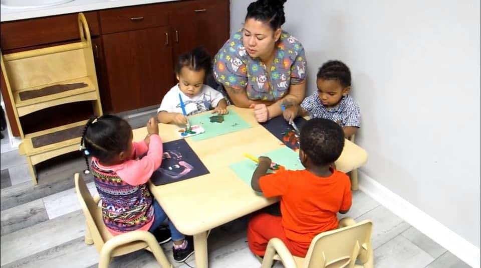 Adult and four children sitting at a table doing crafts