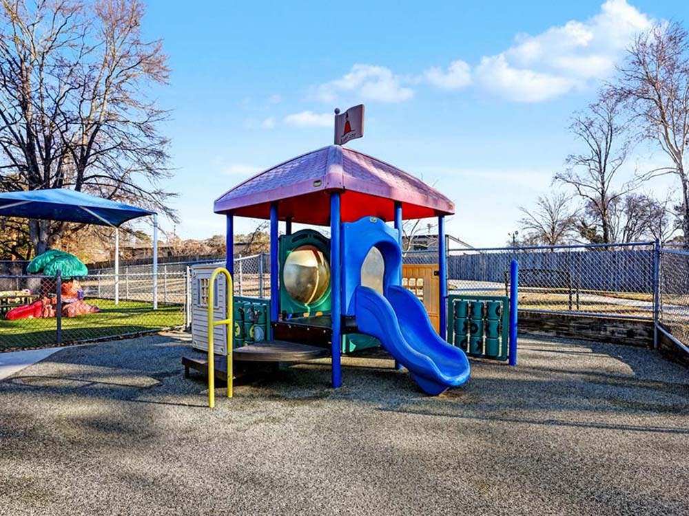a playground with a blue slide and red roof