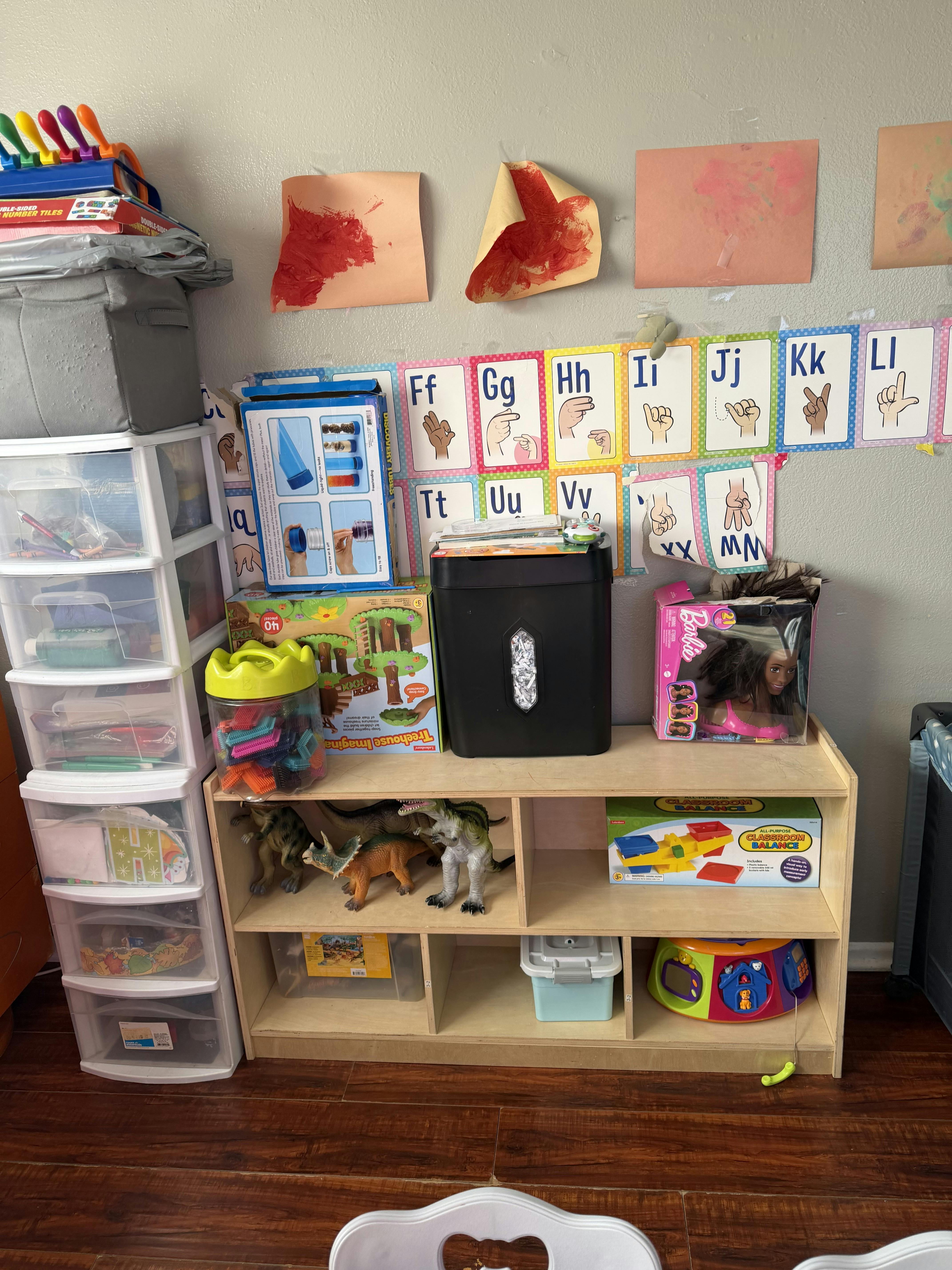 A room with alphabet and ASL charts on the wall, and various toys and craft supplies