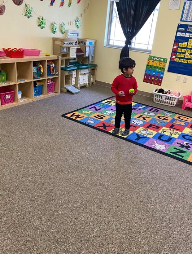 Child standing on an alphabet rug in a classroom