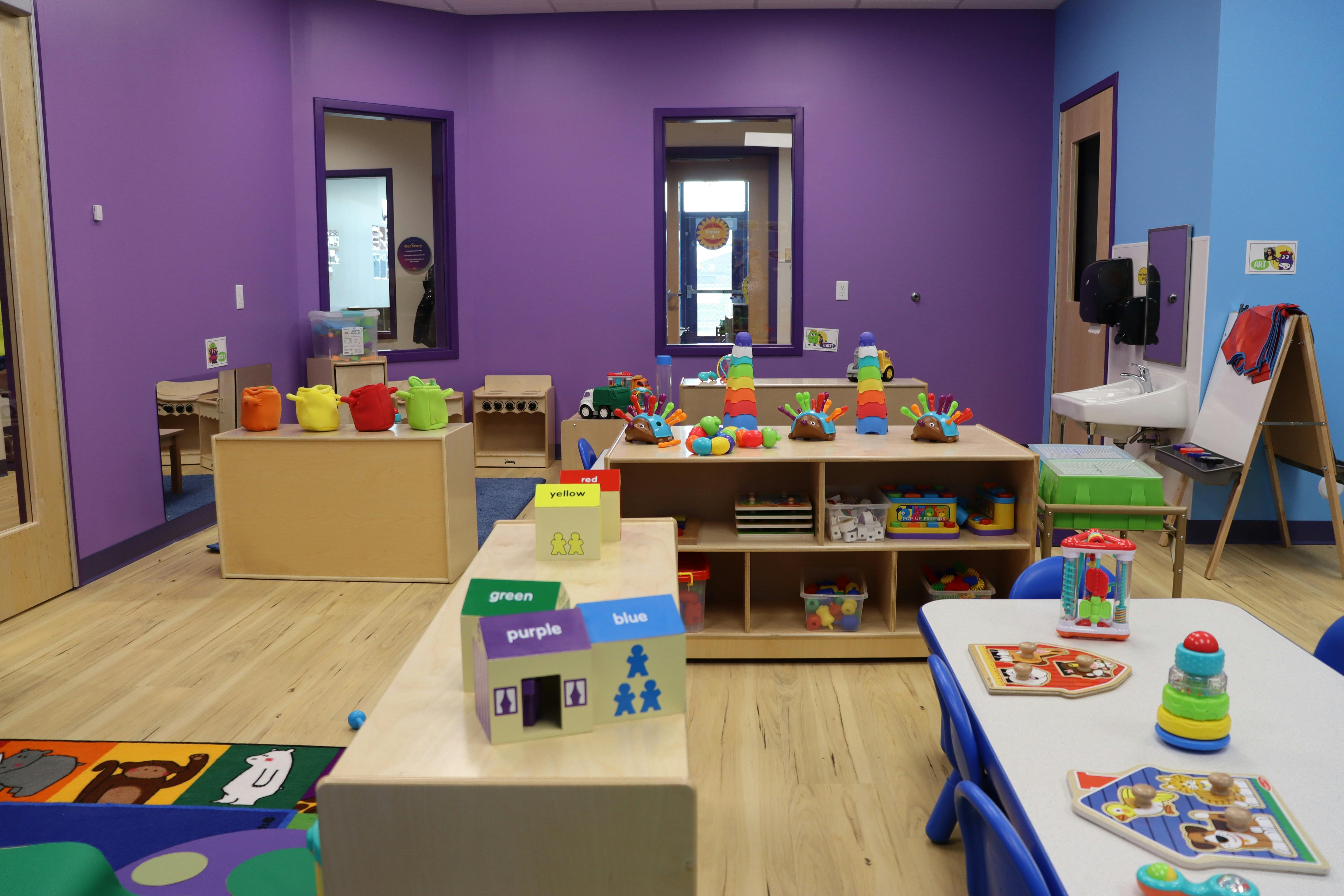 Classroom with purple and blue walls, tables, and various colorful toys