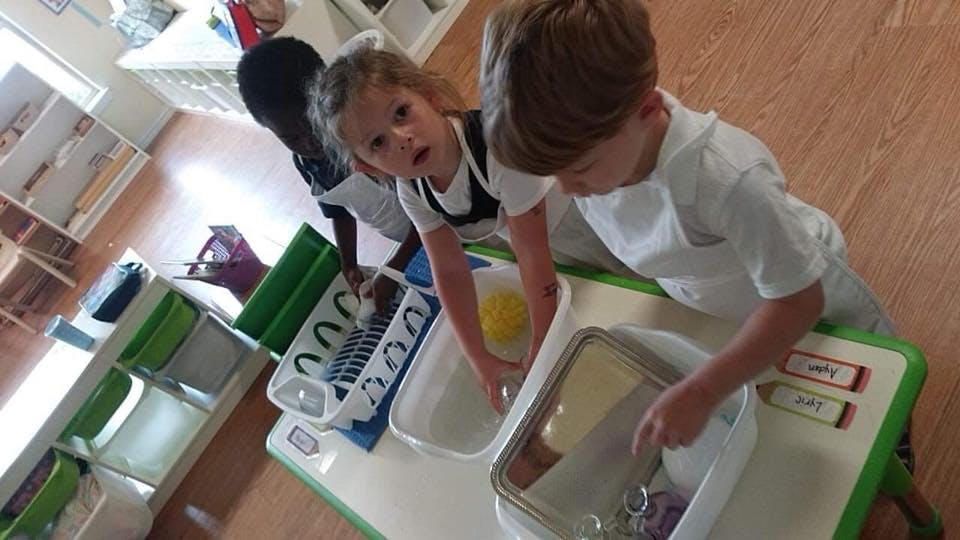 Two children washing dishes in a classroom