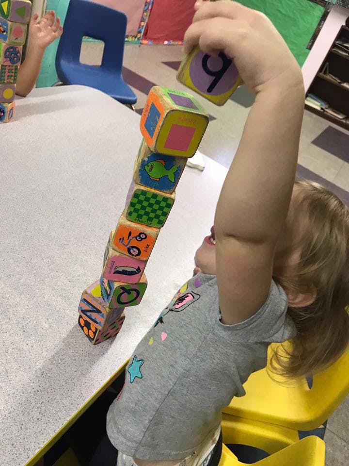 Child stacking colorful blocks on a table
