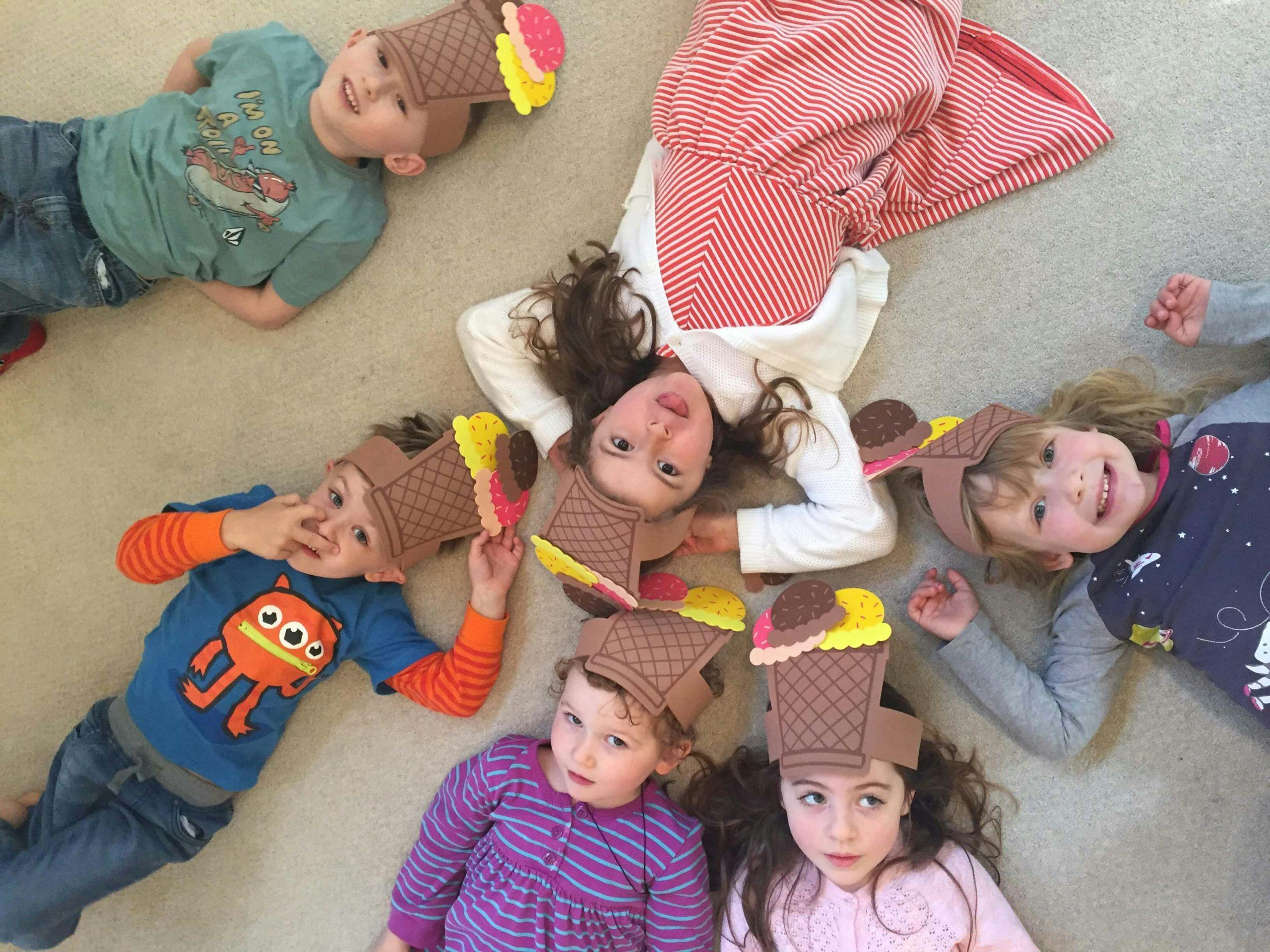 Children lying on the floor wearing ice cream cone hats