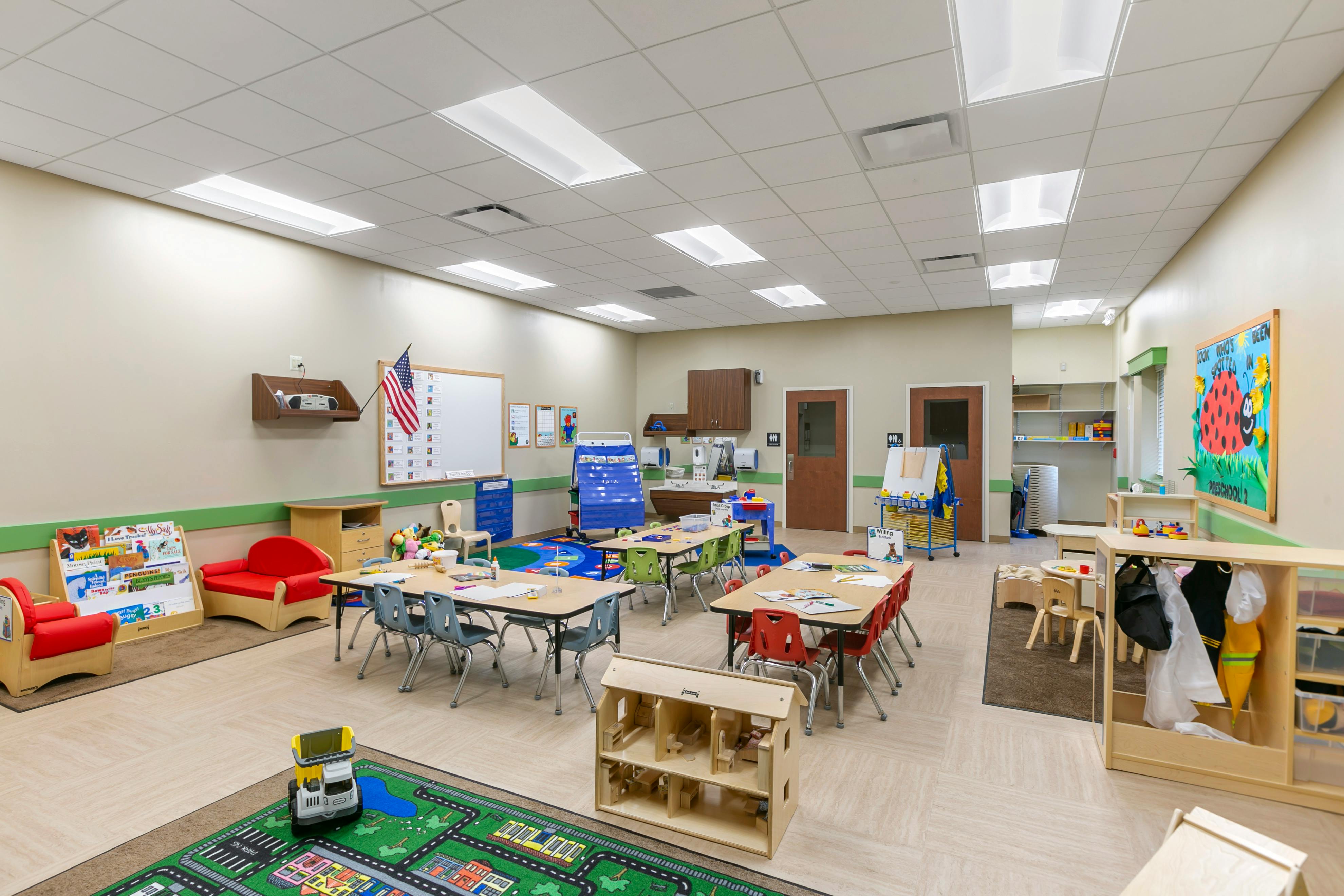 An empty early childhood classroom with multiple activity areas and small furniture