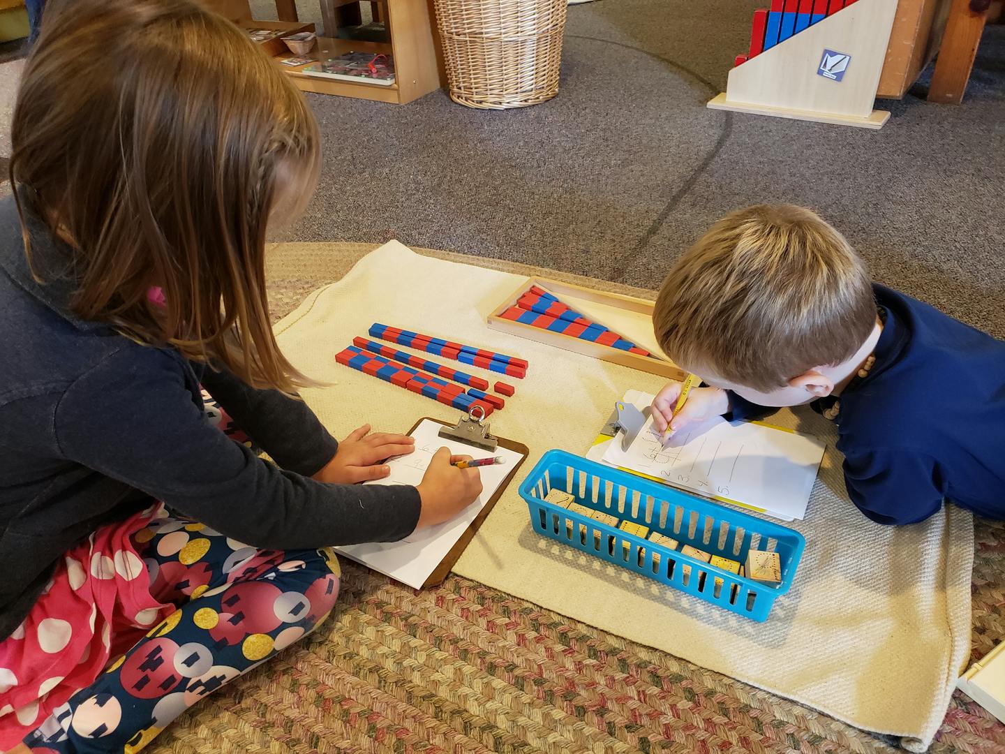 Two children working on a mat with learning materials