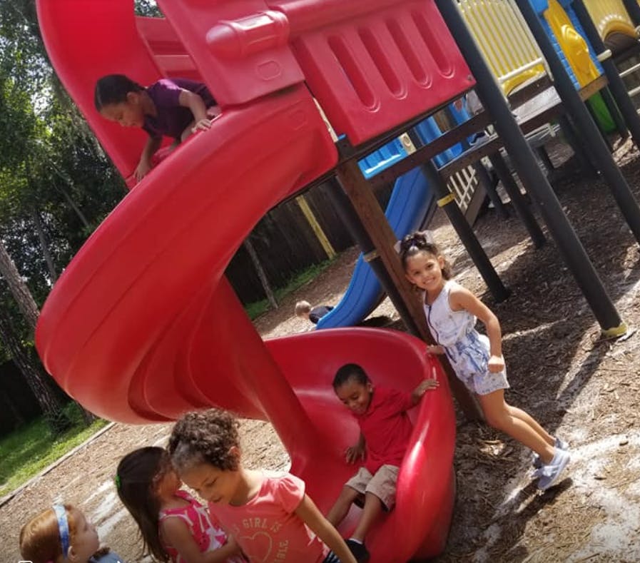 Children playing on a red playground slide