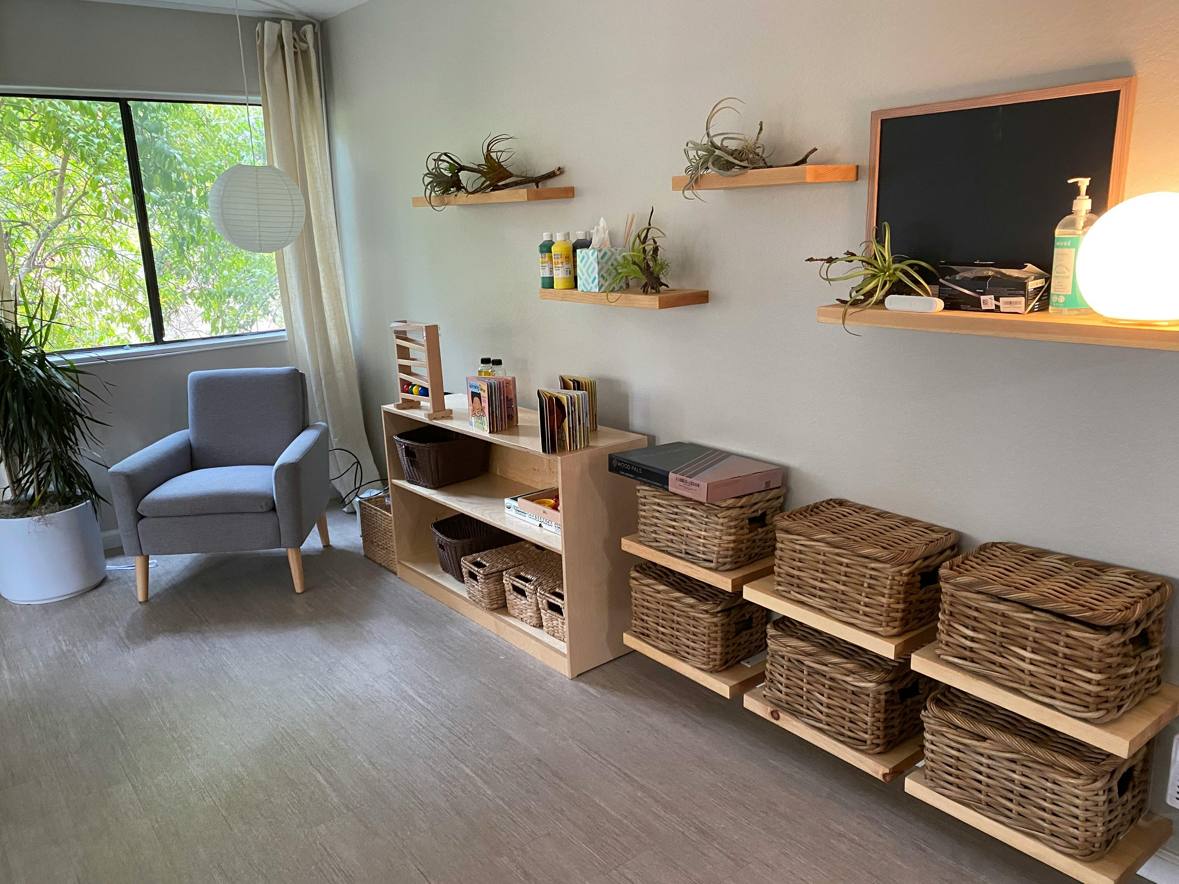 Room with a gray armchair, shelves with baskets, and a window