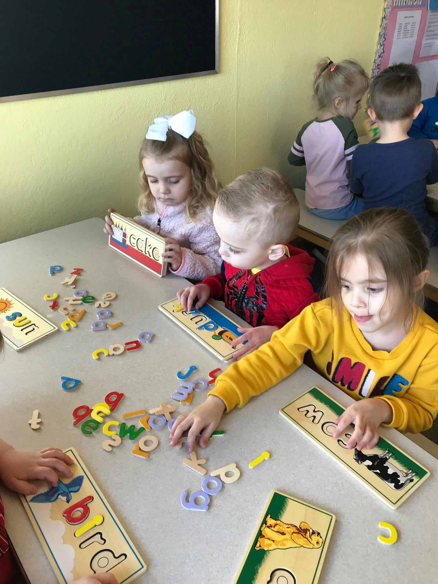 Children playing with letter puzzles at a table