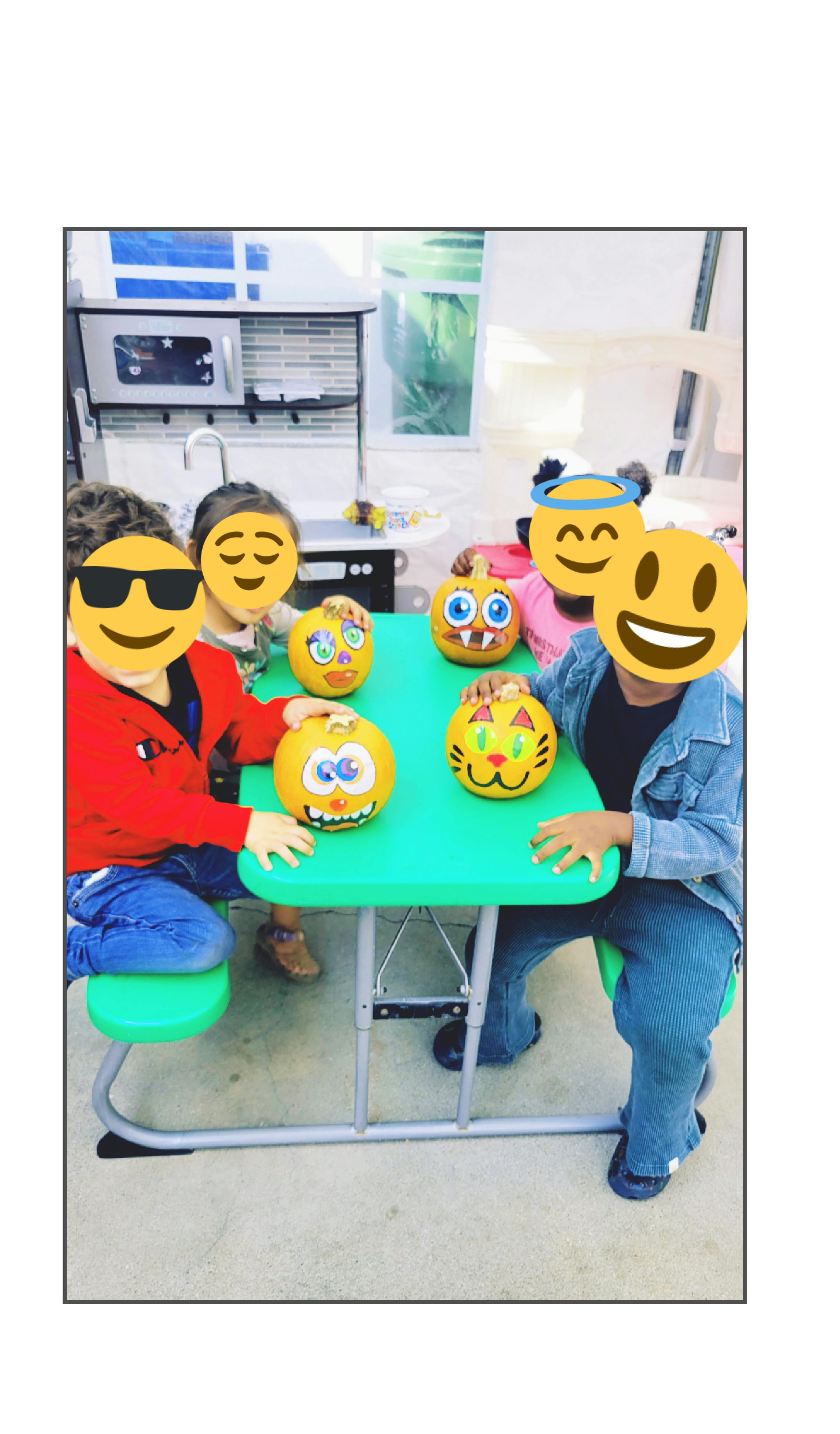 Children sitting at a table with decorated pumpkins