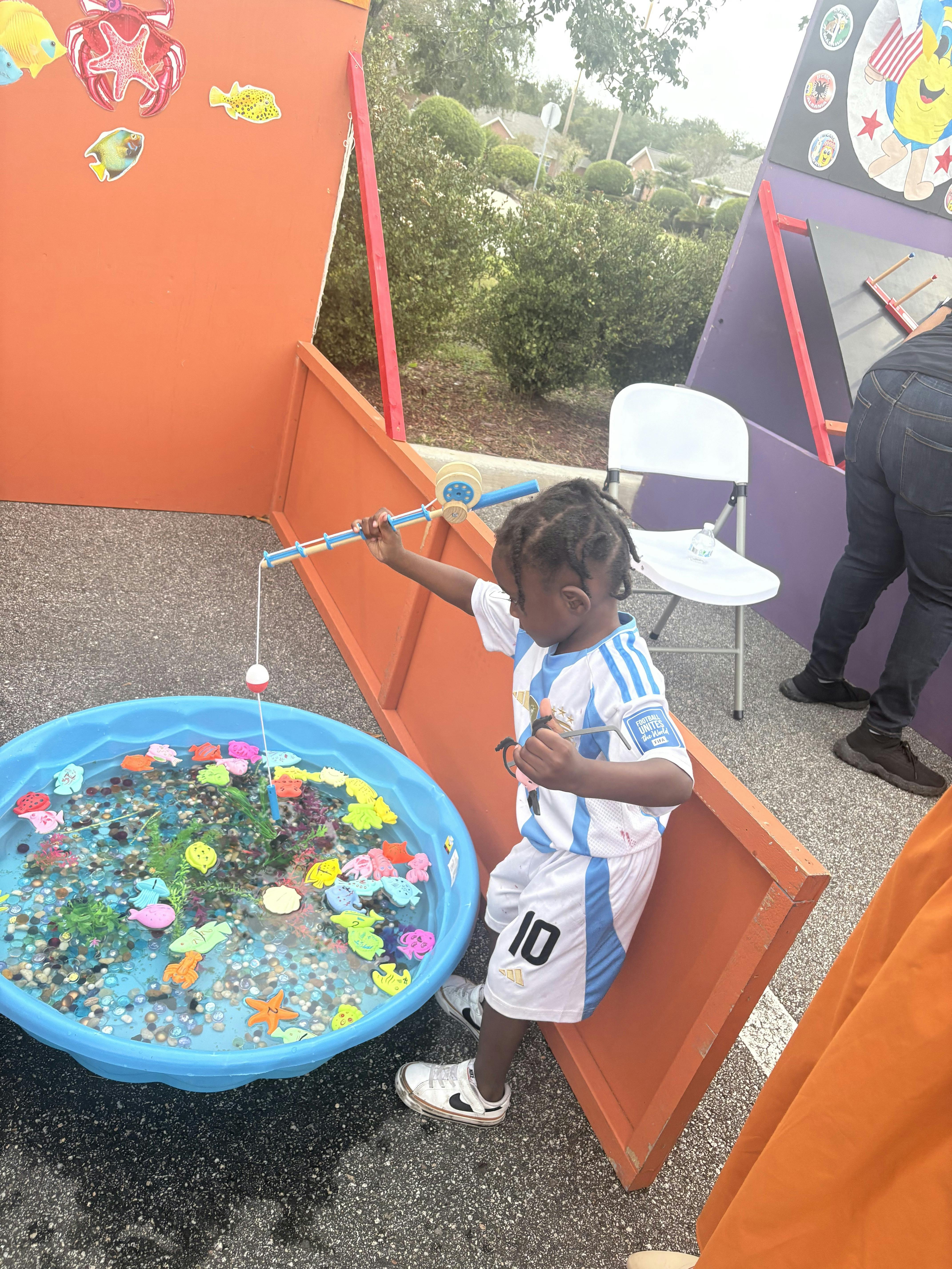 Child playing a fishing game with a toy rod in a small pool