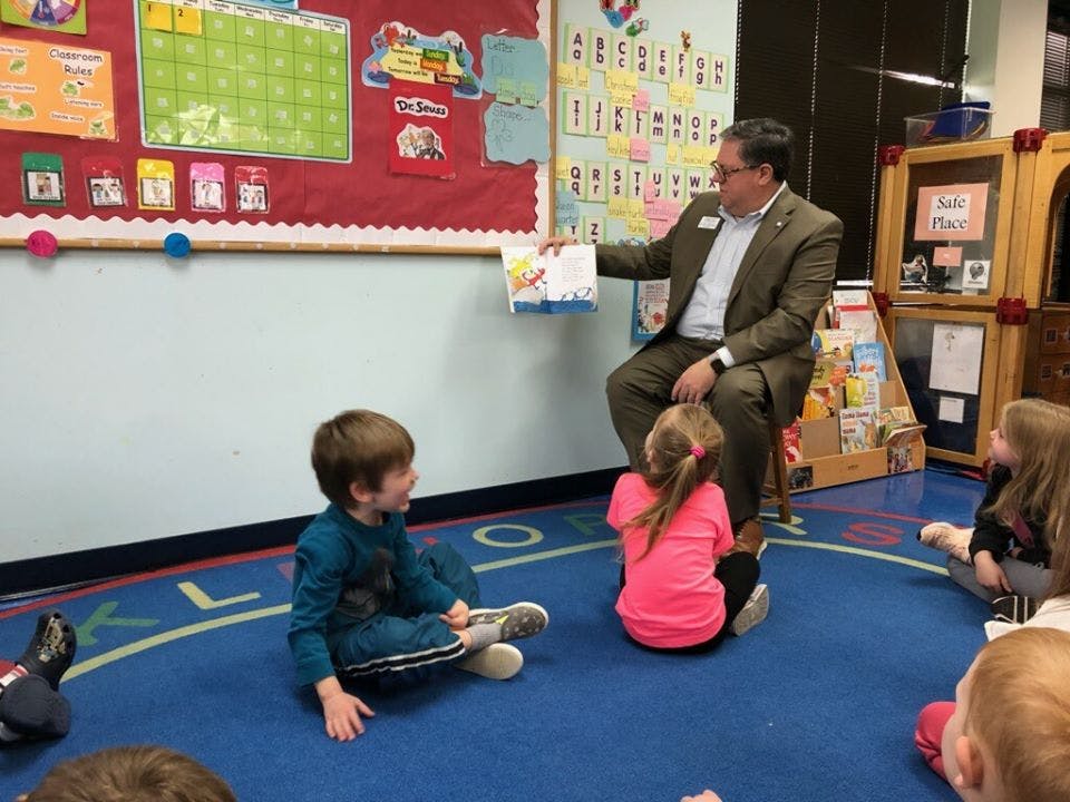 Adult reading a book to children in a classroom