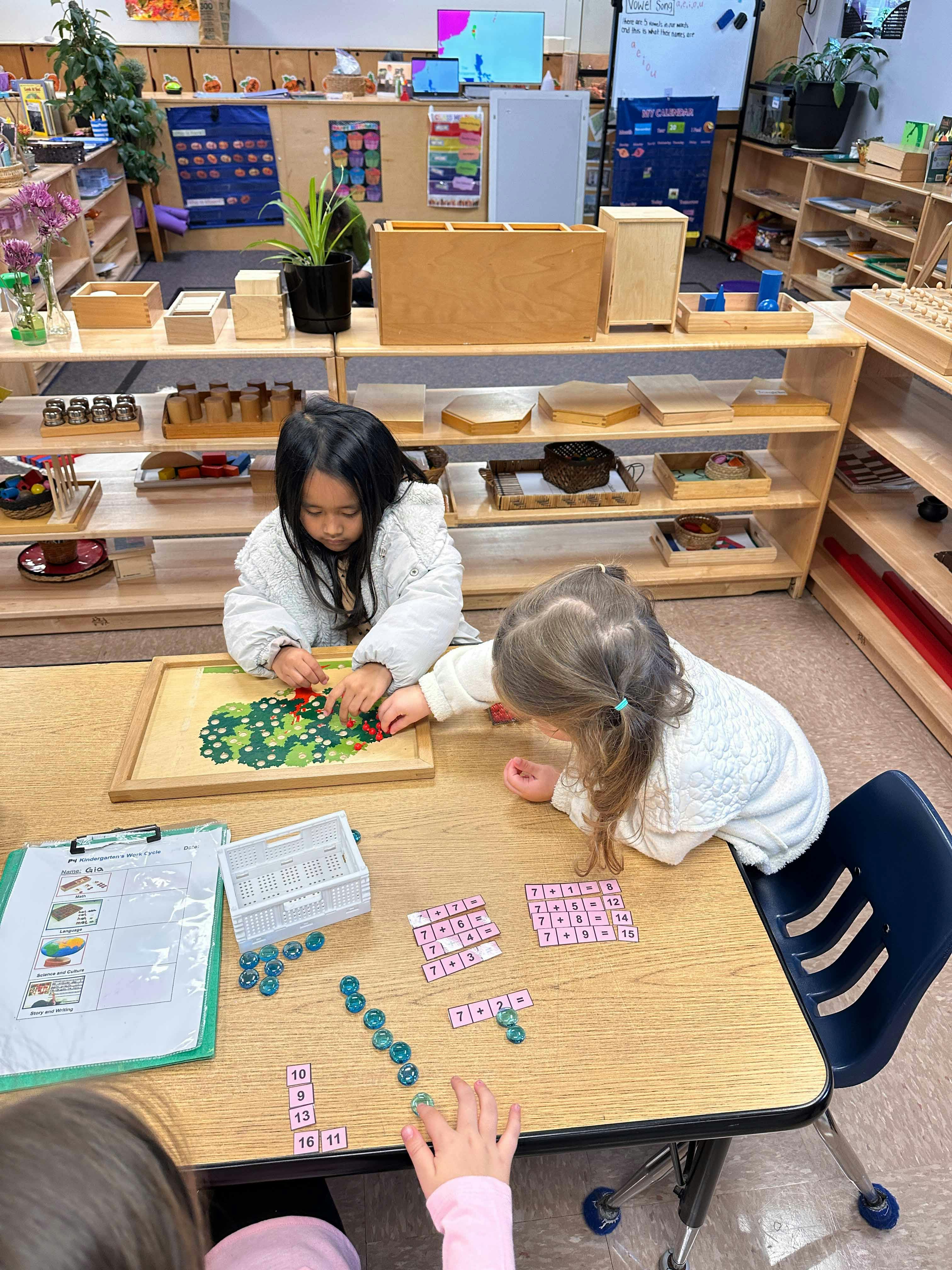 Two children playing with learning materials at a table in a classroom