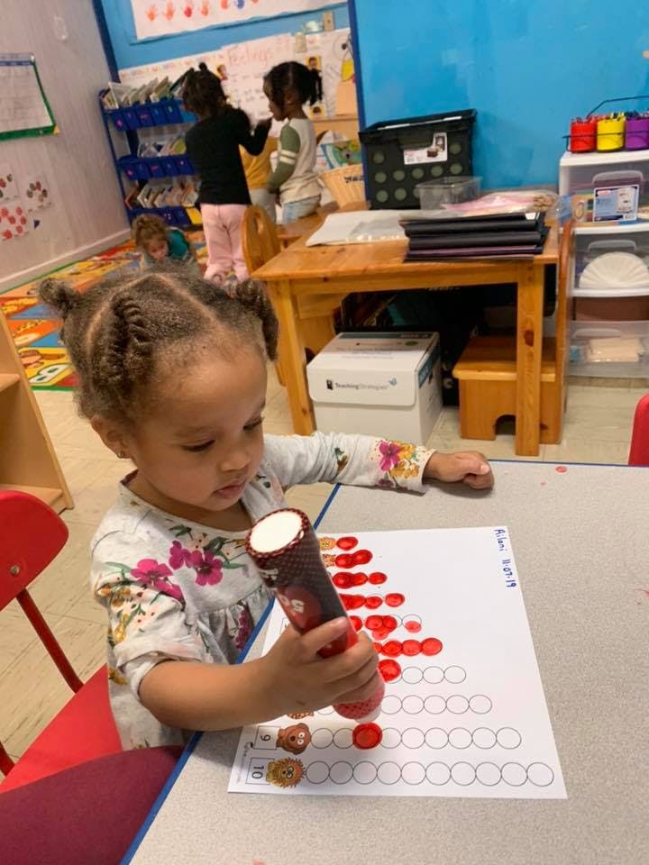 Child using a dot marker on a worksheet at a table