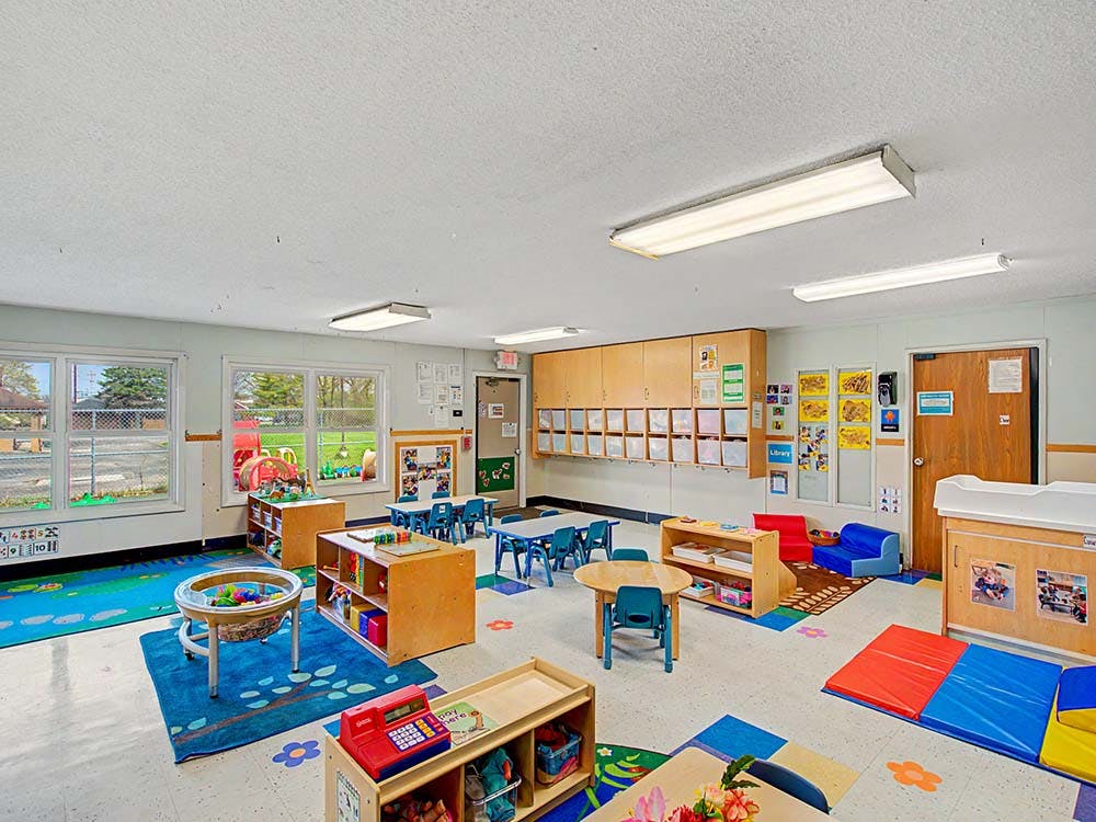 Empty colorful preschool classroom with small tables and chairs