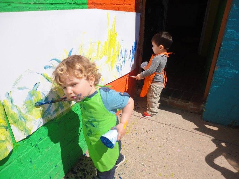 Two children painting on a wall