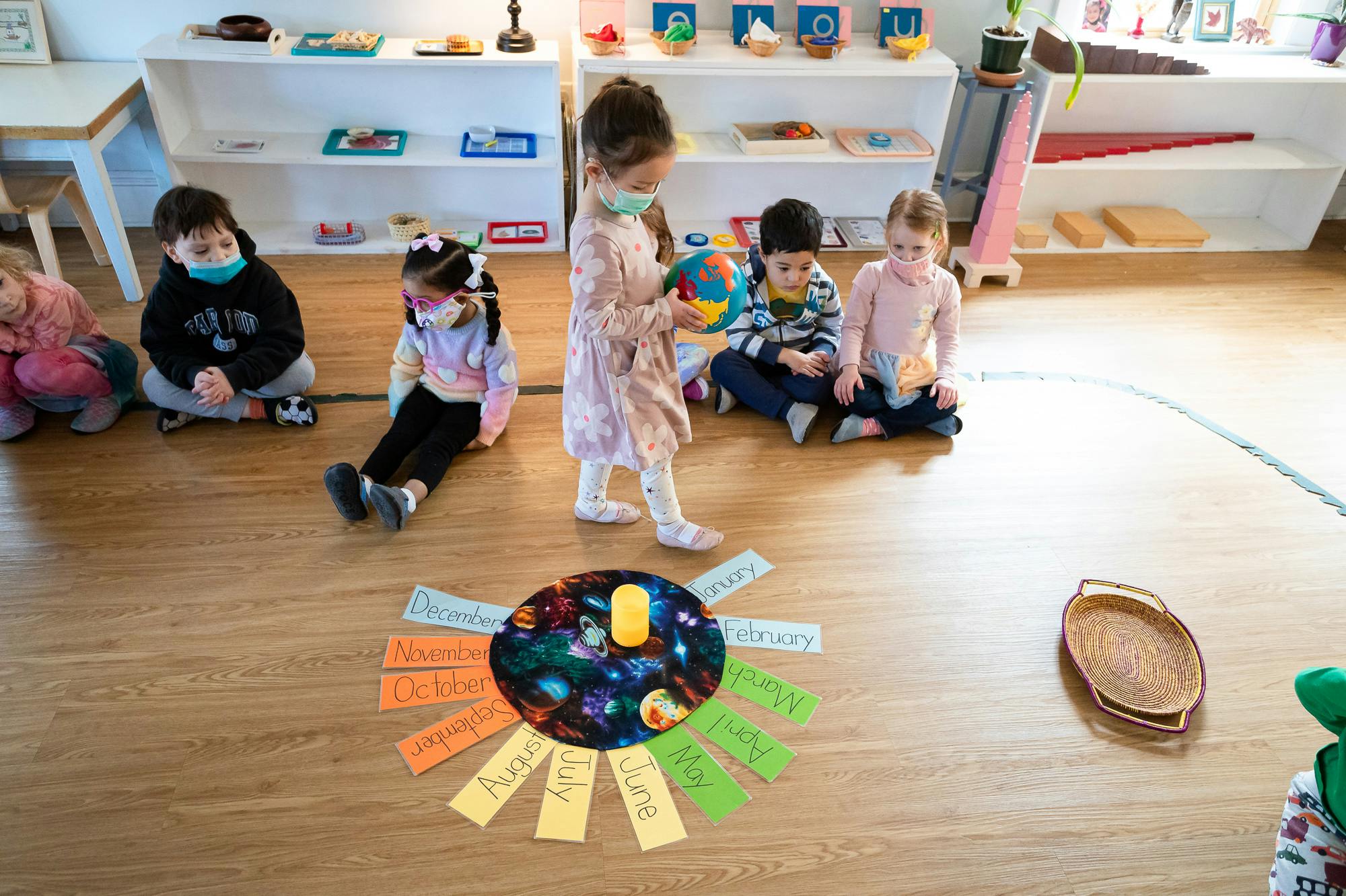 Children in masks playing on the floor in a classroom