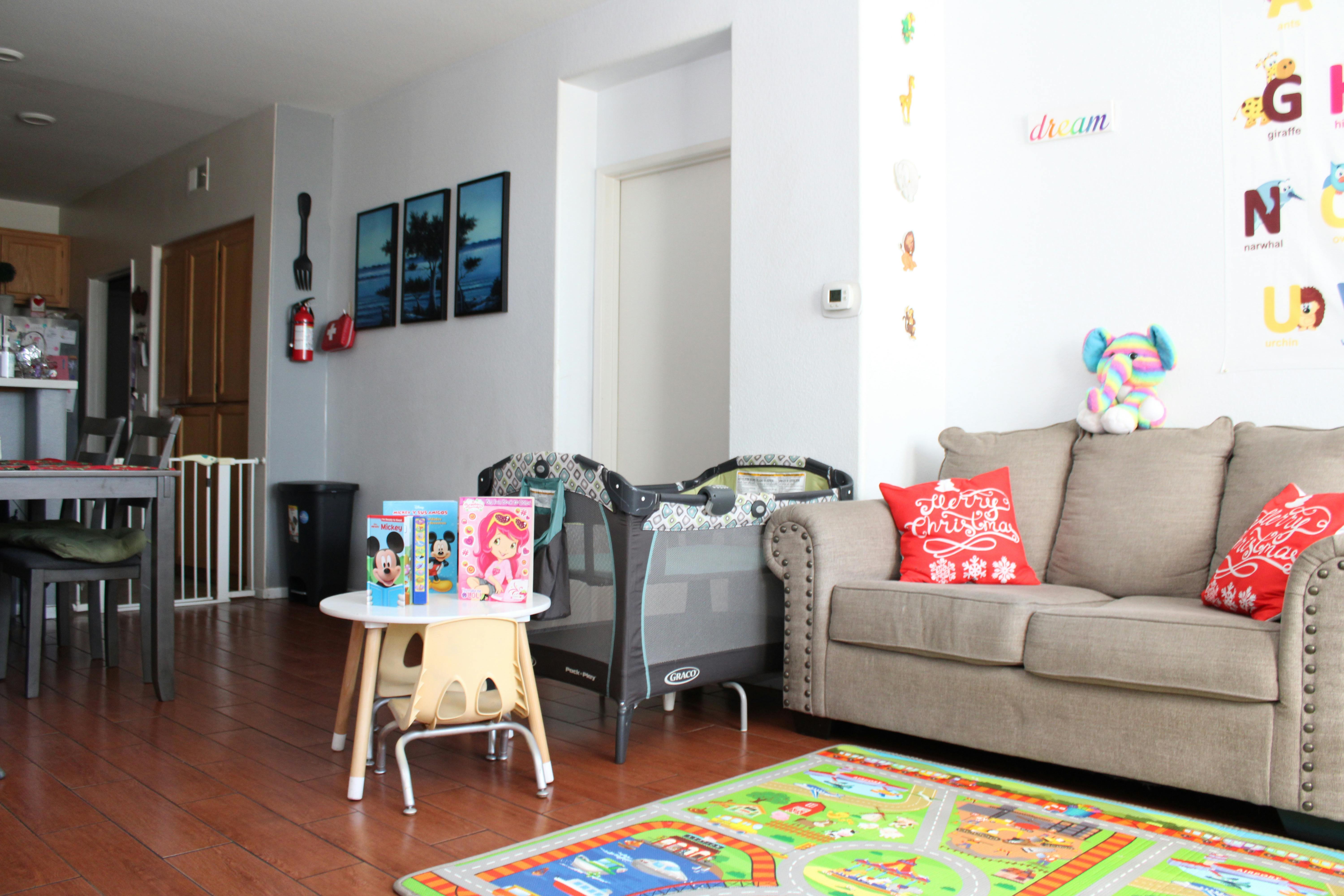 Childs small table with books next to a playpen in a living room