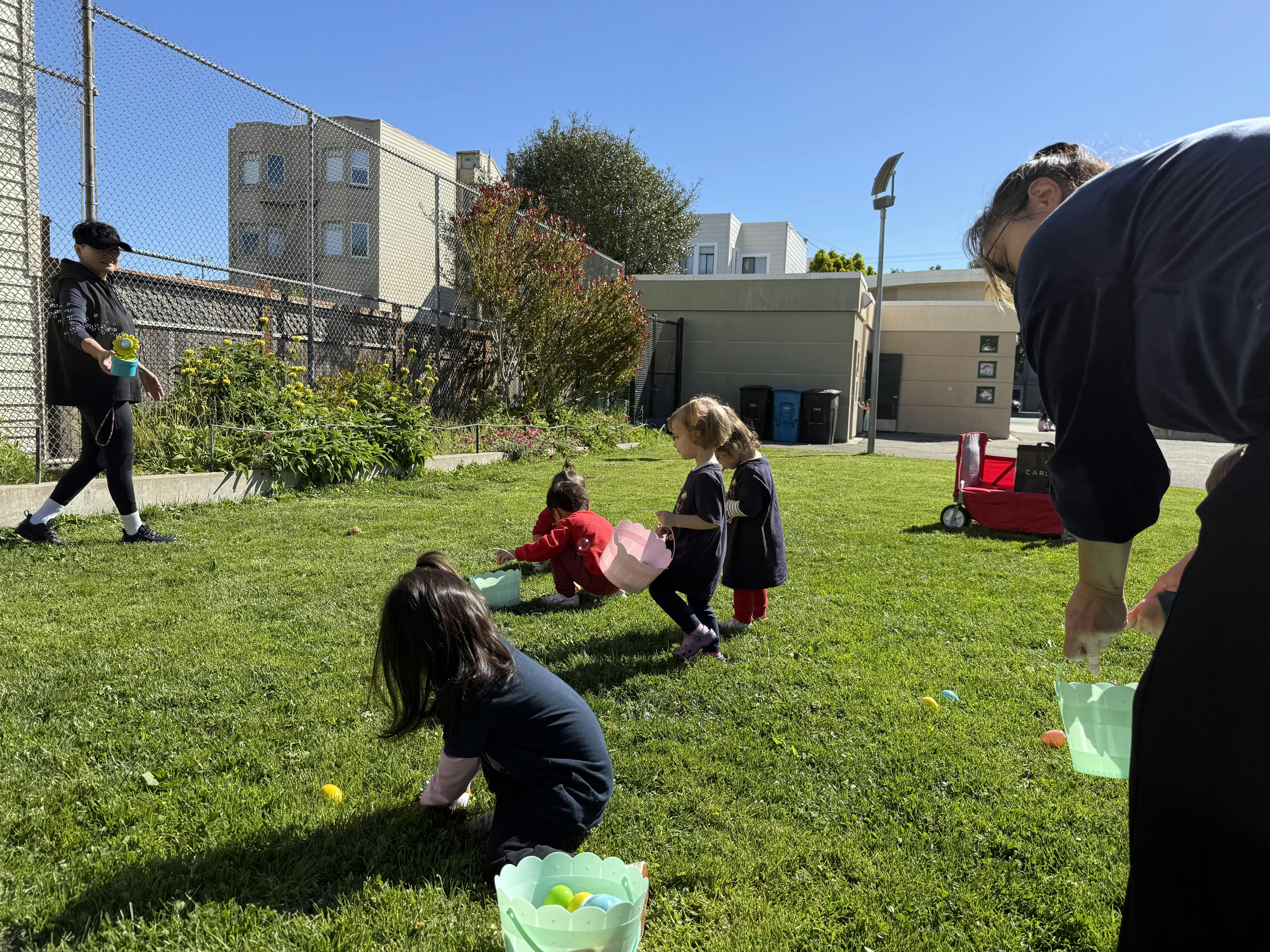 Adults and children collecting Easter eggs in baskets on a grassy lawn