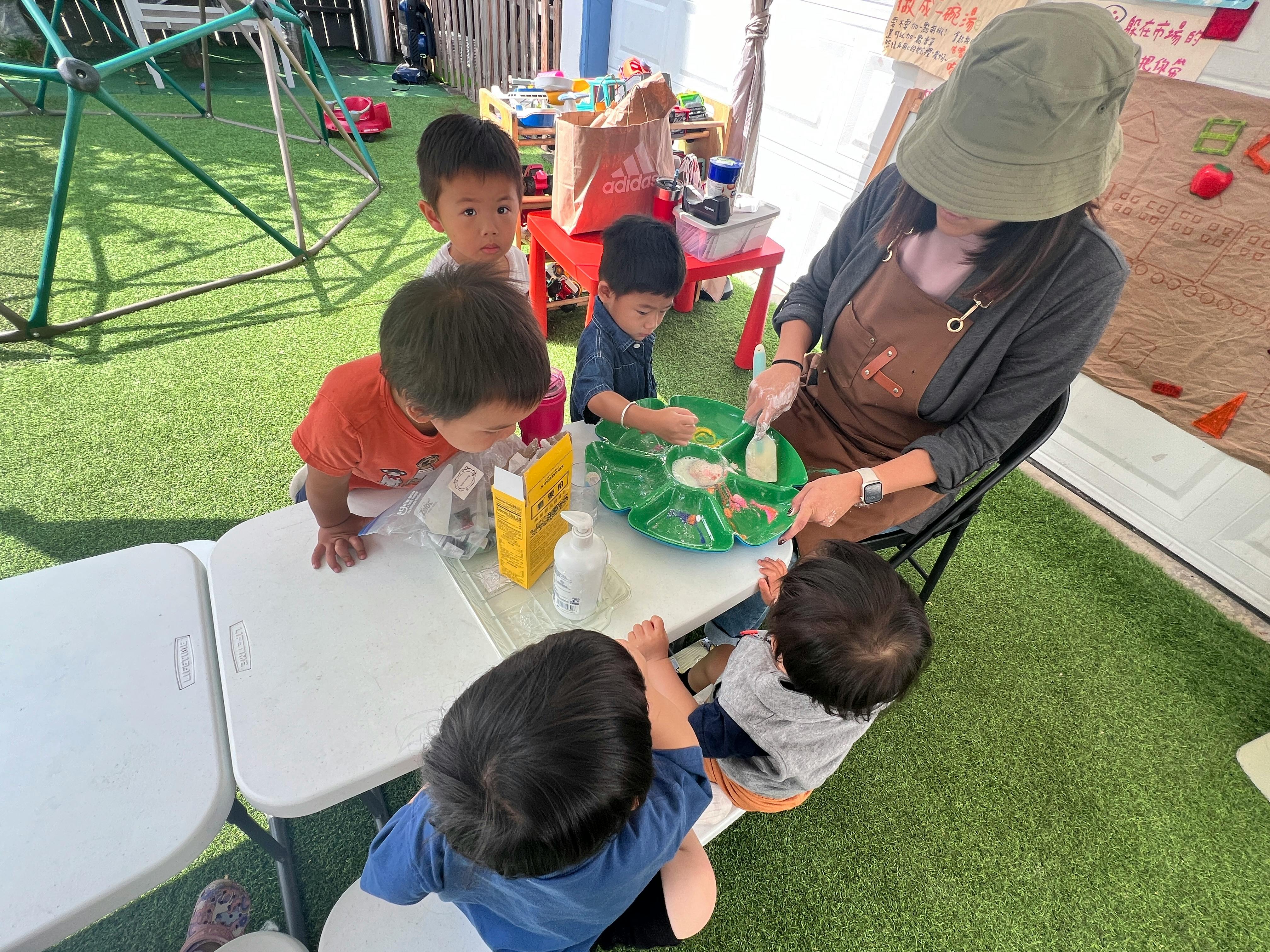 Person and children at a table with a green tray