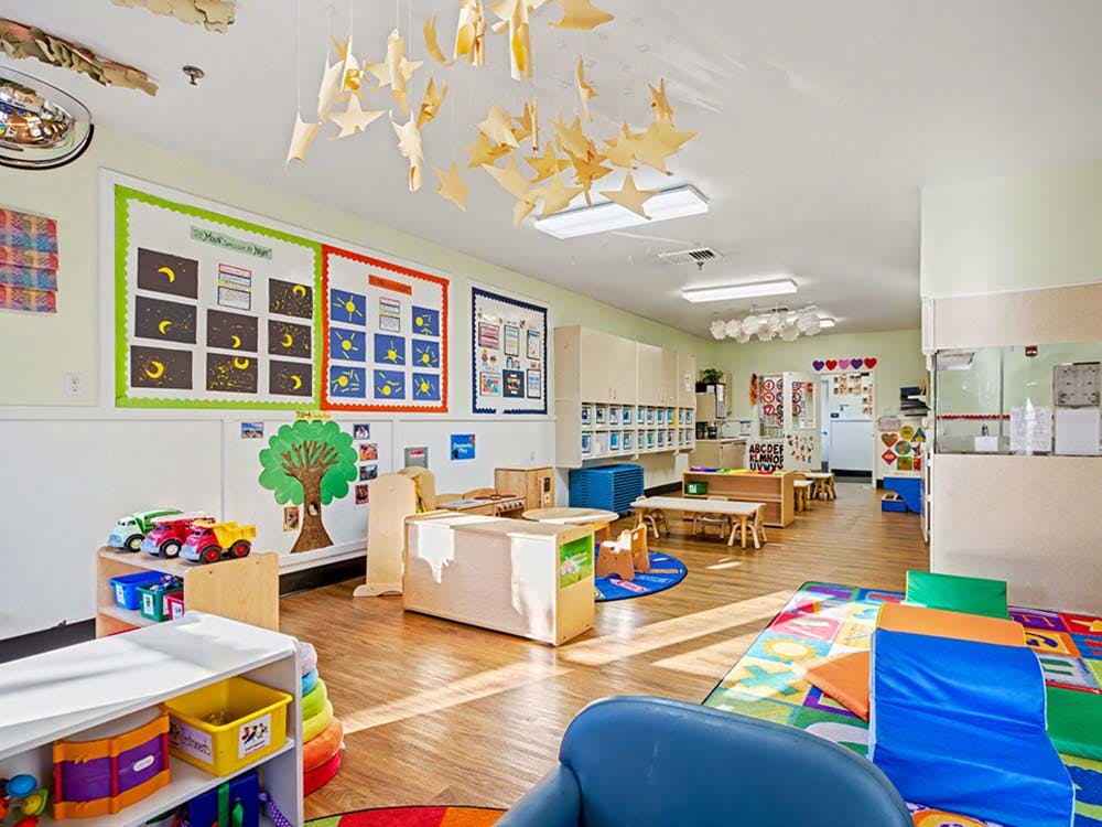 Colorful classroom with educational posters, small tables, and play mats