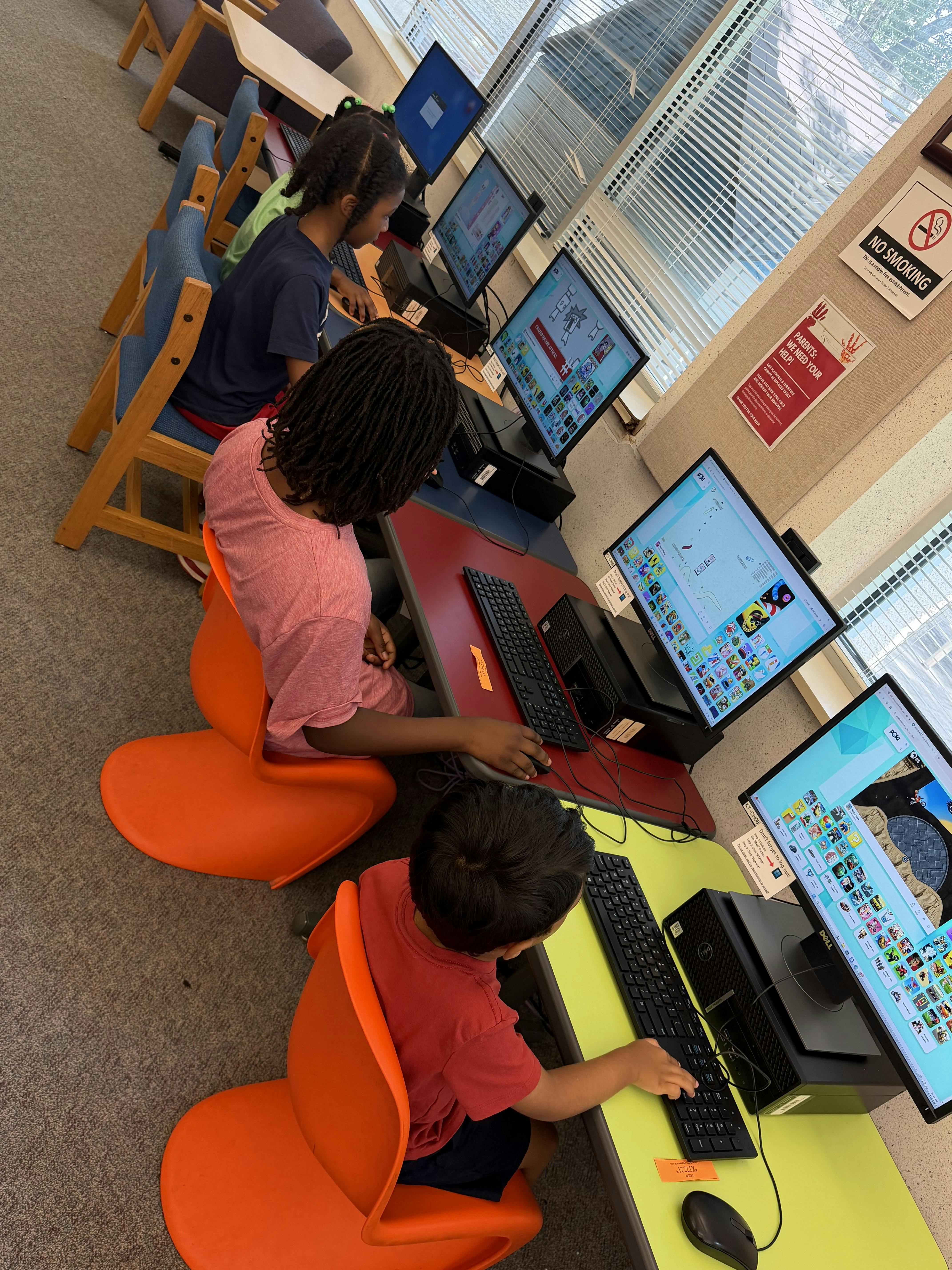 Children using desktop computers in a row at a library or school