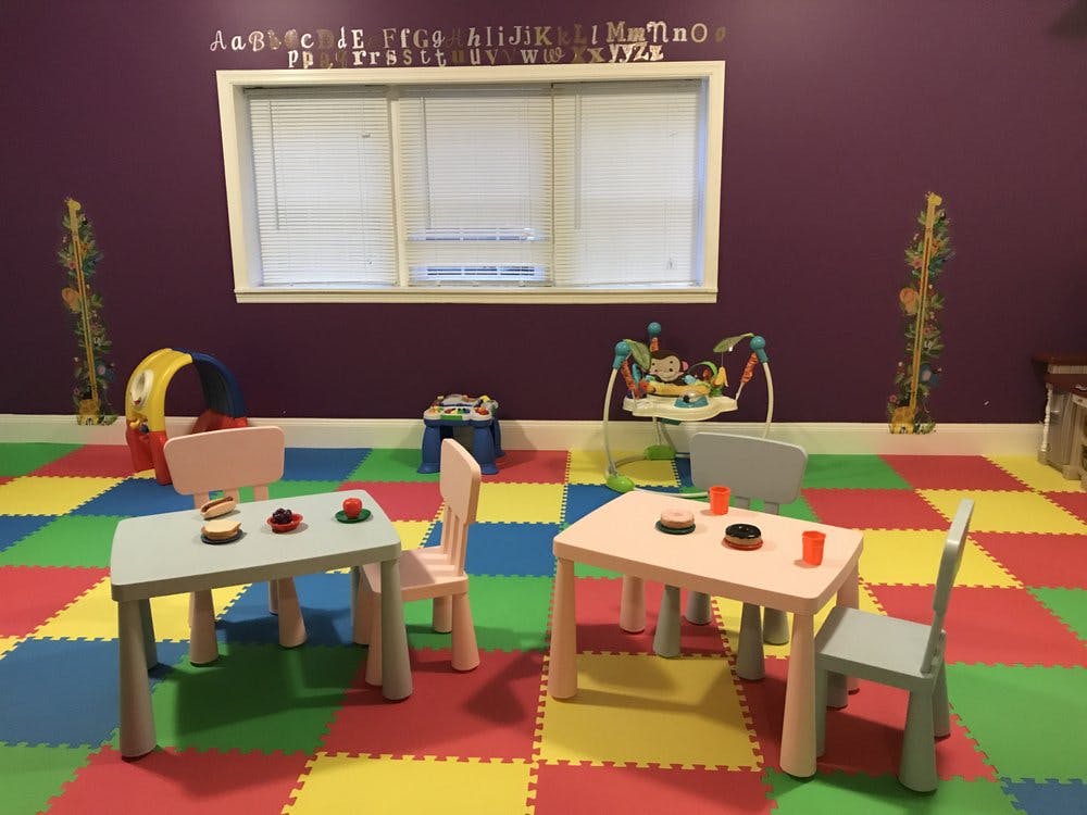 Small tables and chairs for children with play food in a colorful playroom