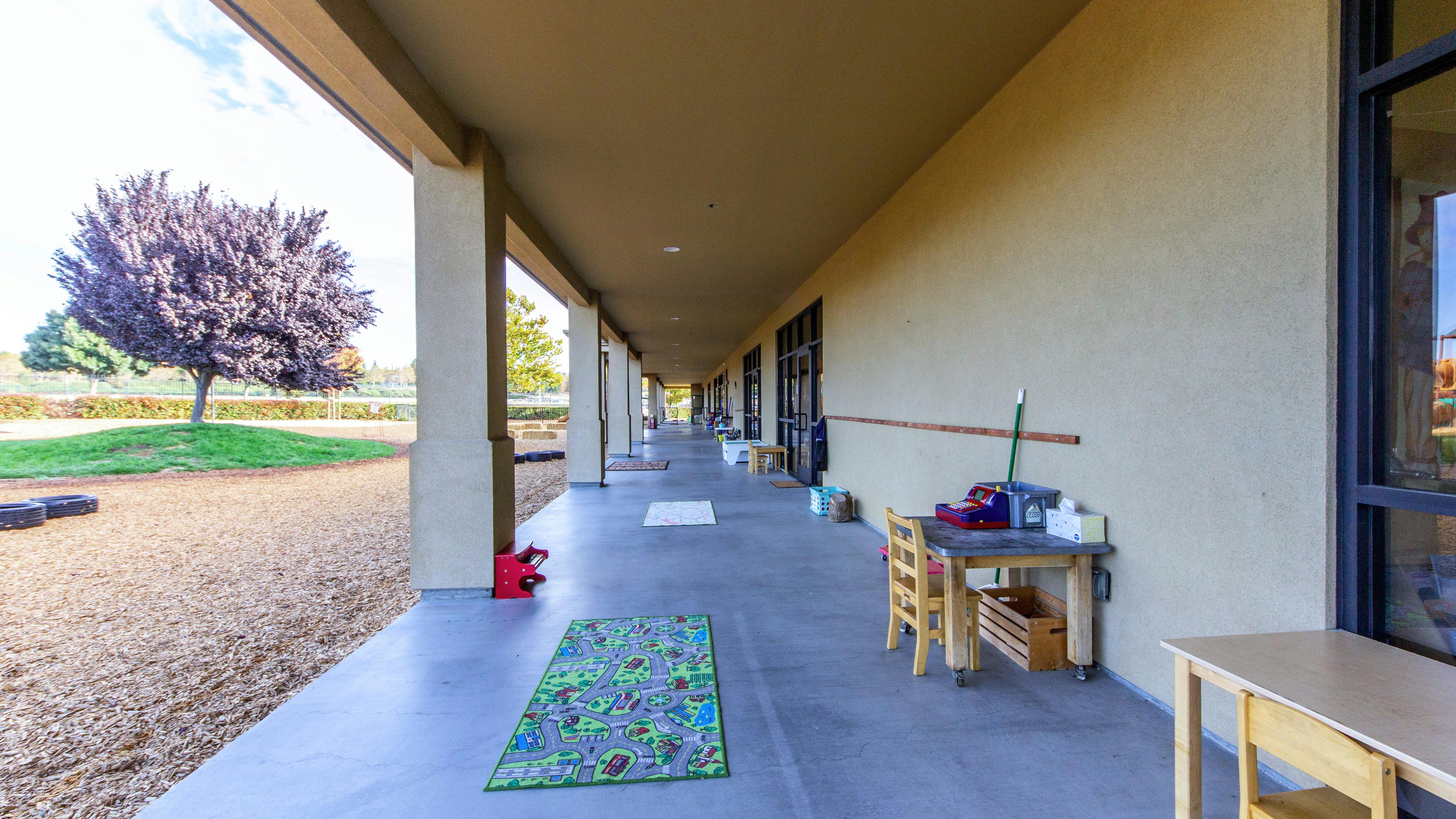 Outdoor walkway with a rug, small table, and chairs