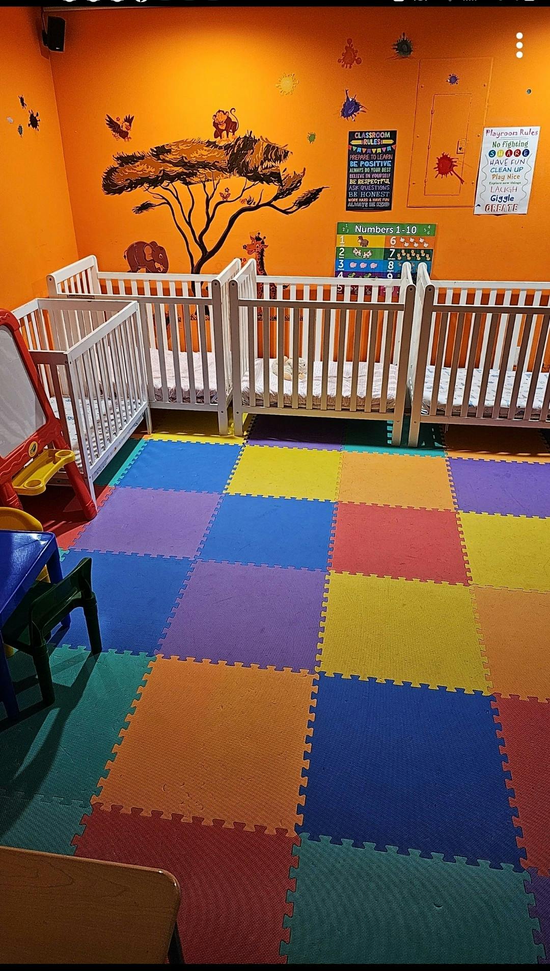 Nursery room with multiple cribs and colorful floor mats