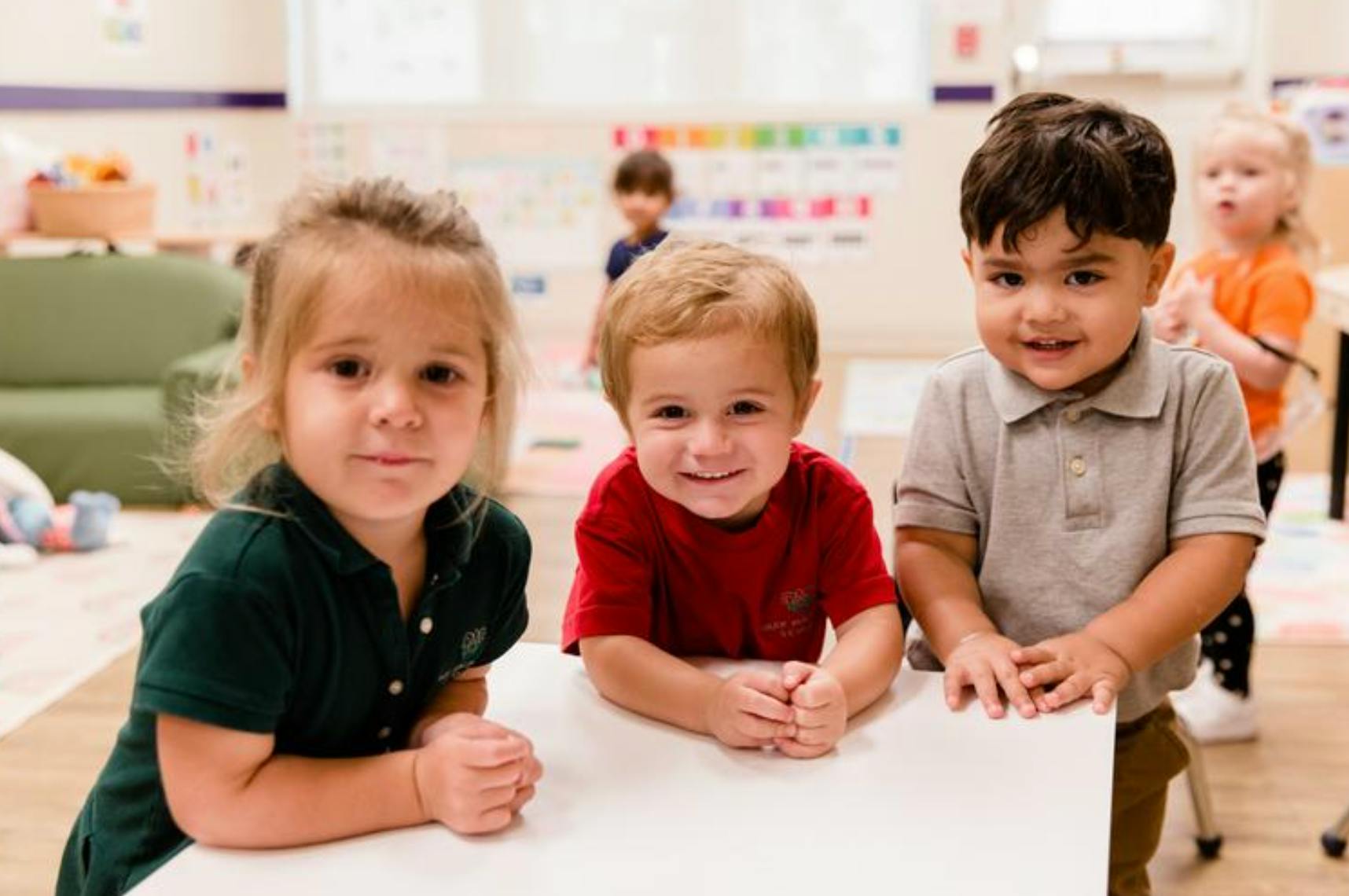 Three young children at a table in a classroom
