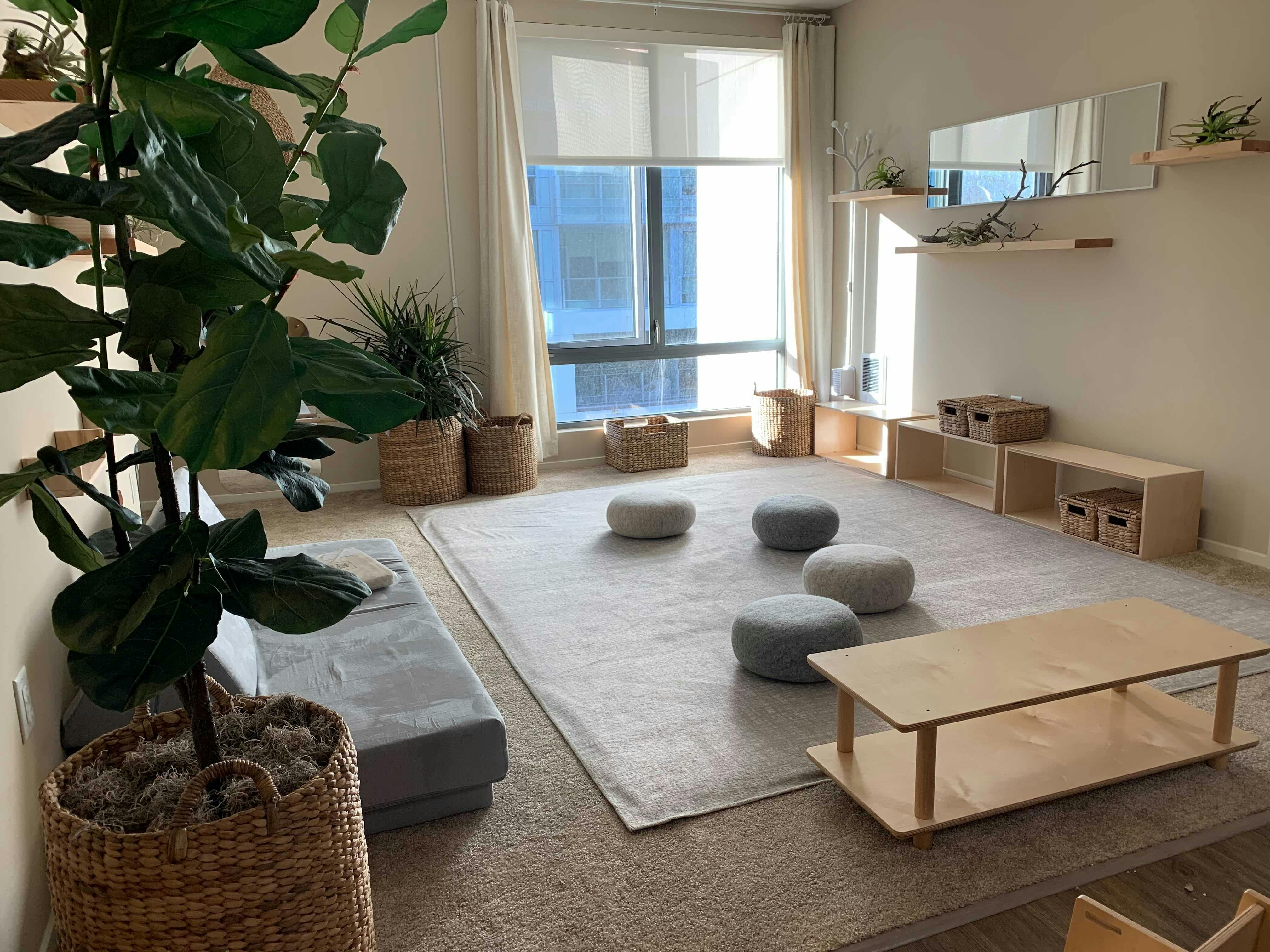 Room with large window, rug, floor cushions, and low wooden furniture