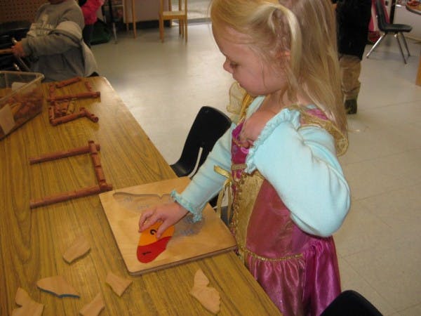 Child playing with a wooden puzzle at a table