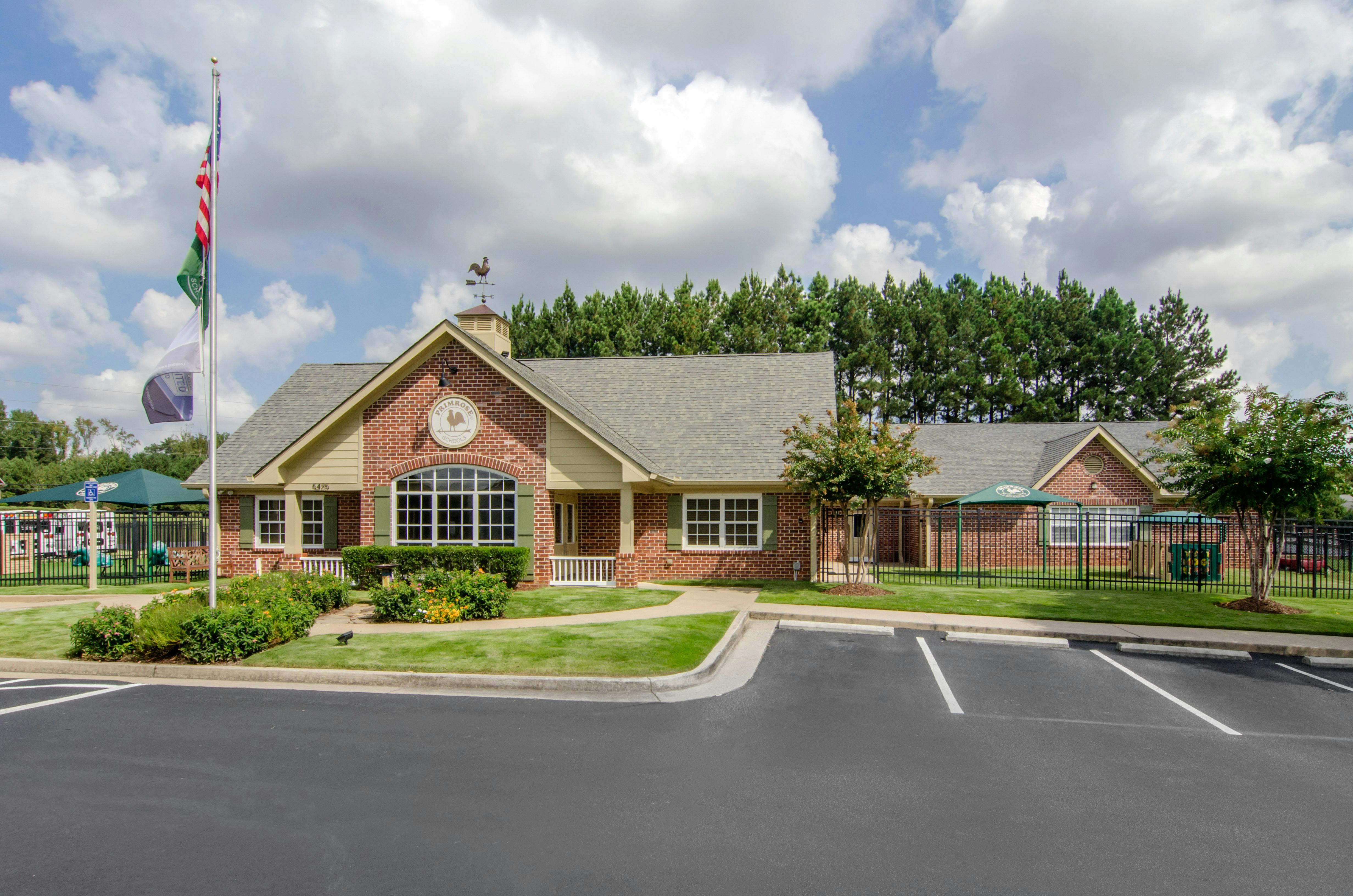 Brick building with a weather vane on the roof, a playground, and a parking lot