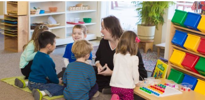 Adult and multiple children sitting on floor in a classroom