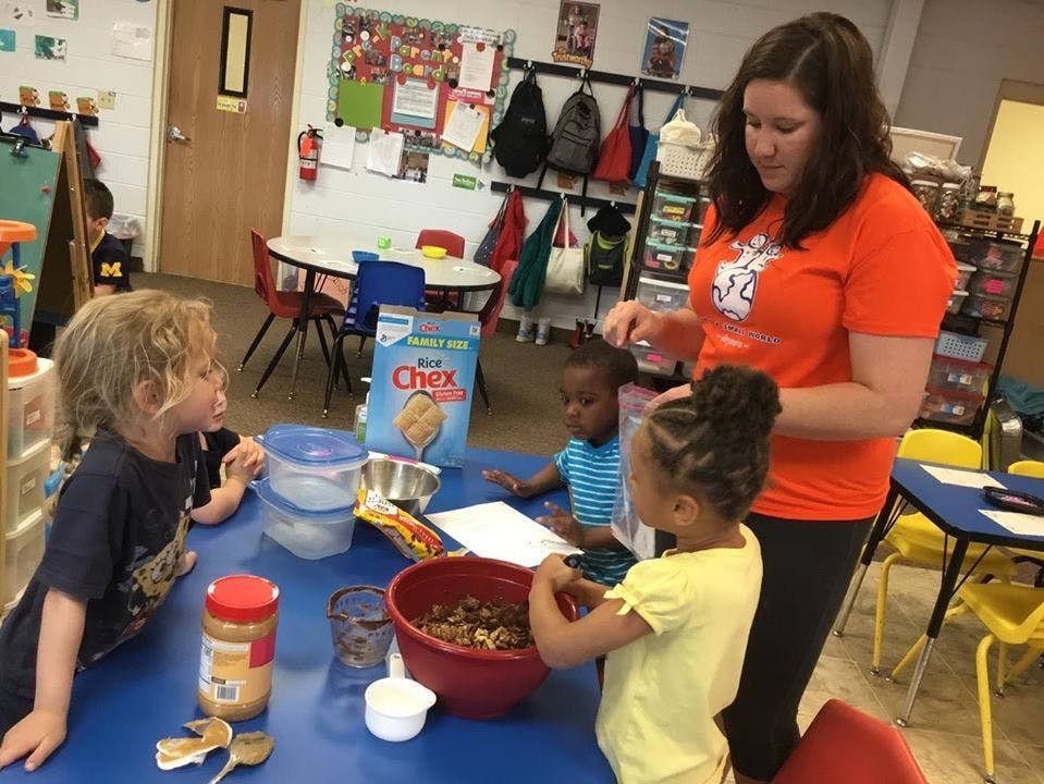 Adult and three children at a table with food items