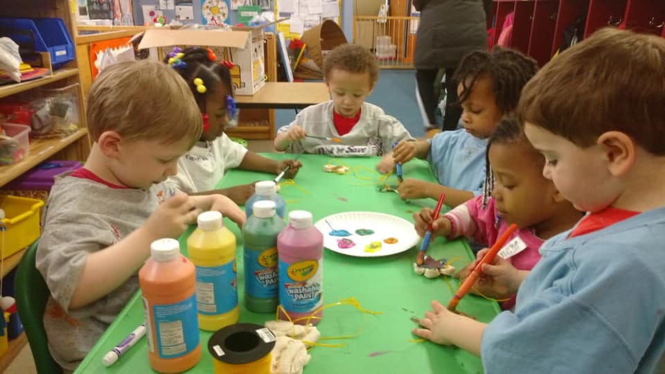 Children painting at a table in a classroom