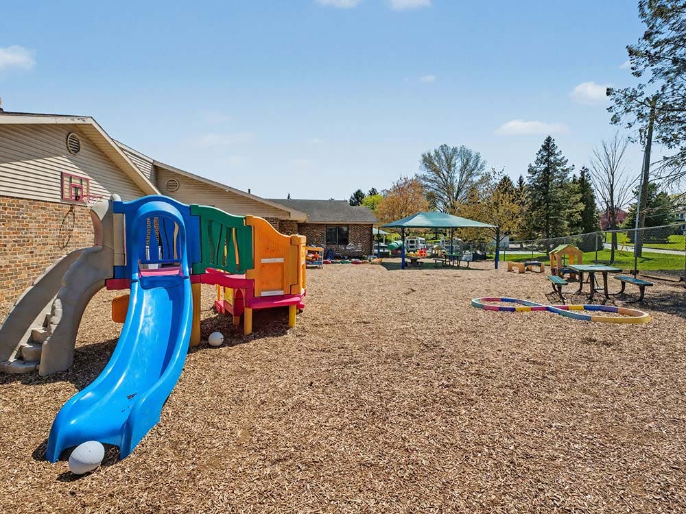 Colorful playground with slide, picnic tables, and wood chips on the ground