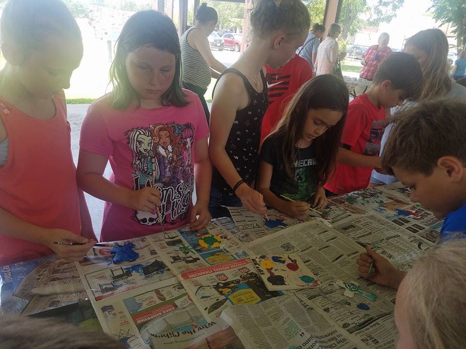 Children painting on newspaper-covered tables