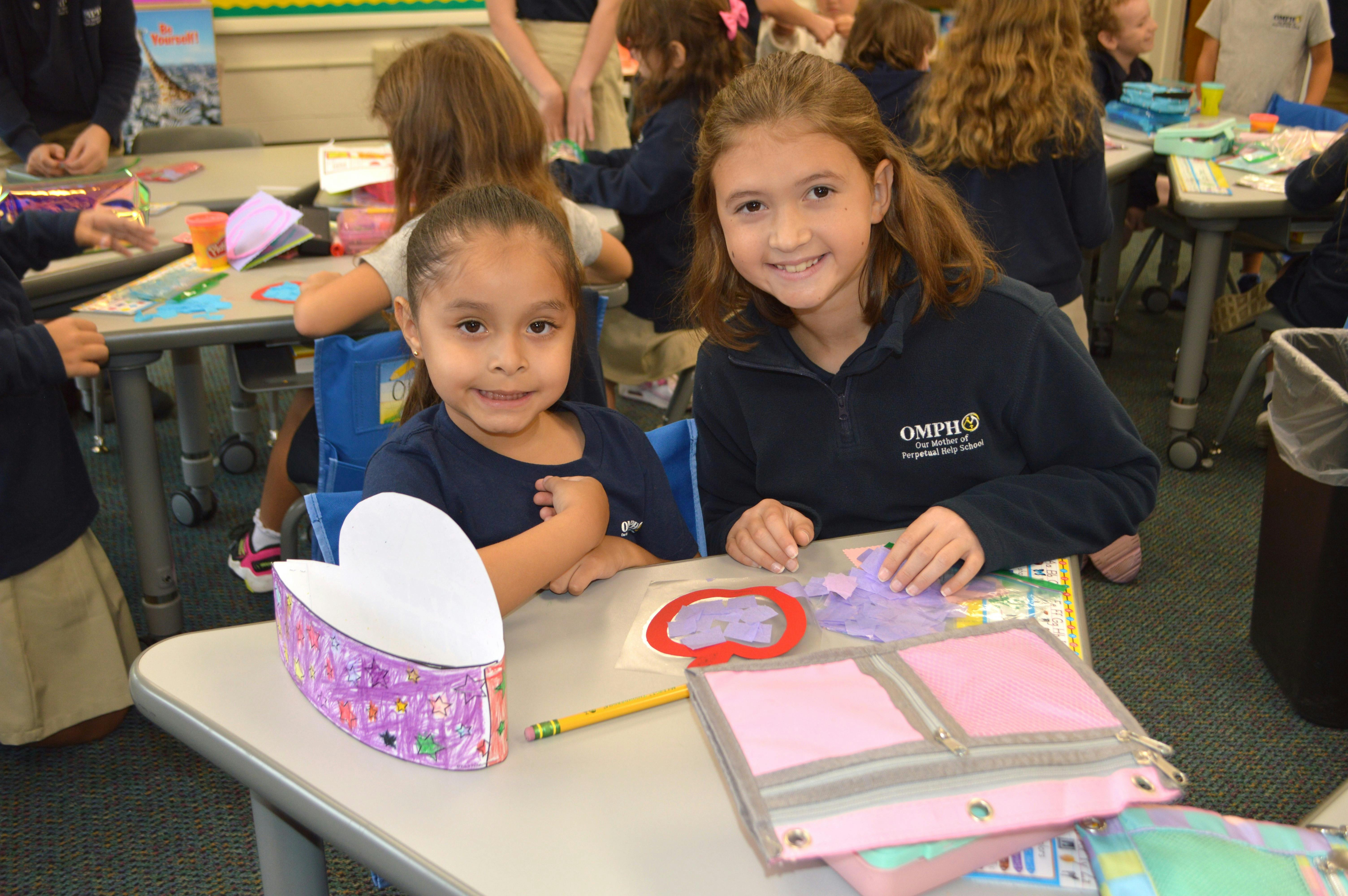 Two children sitting at a table with craft supplies
