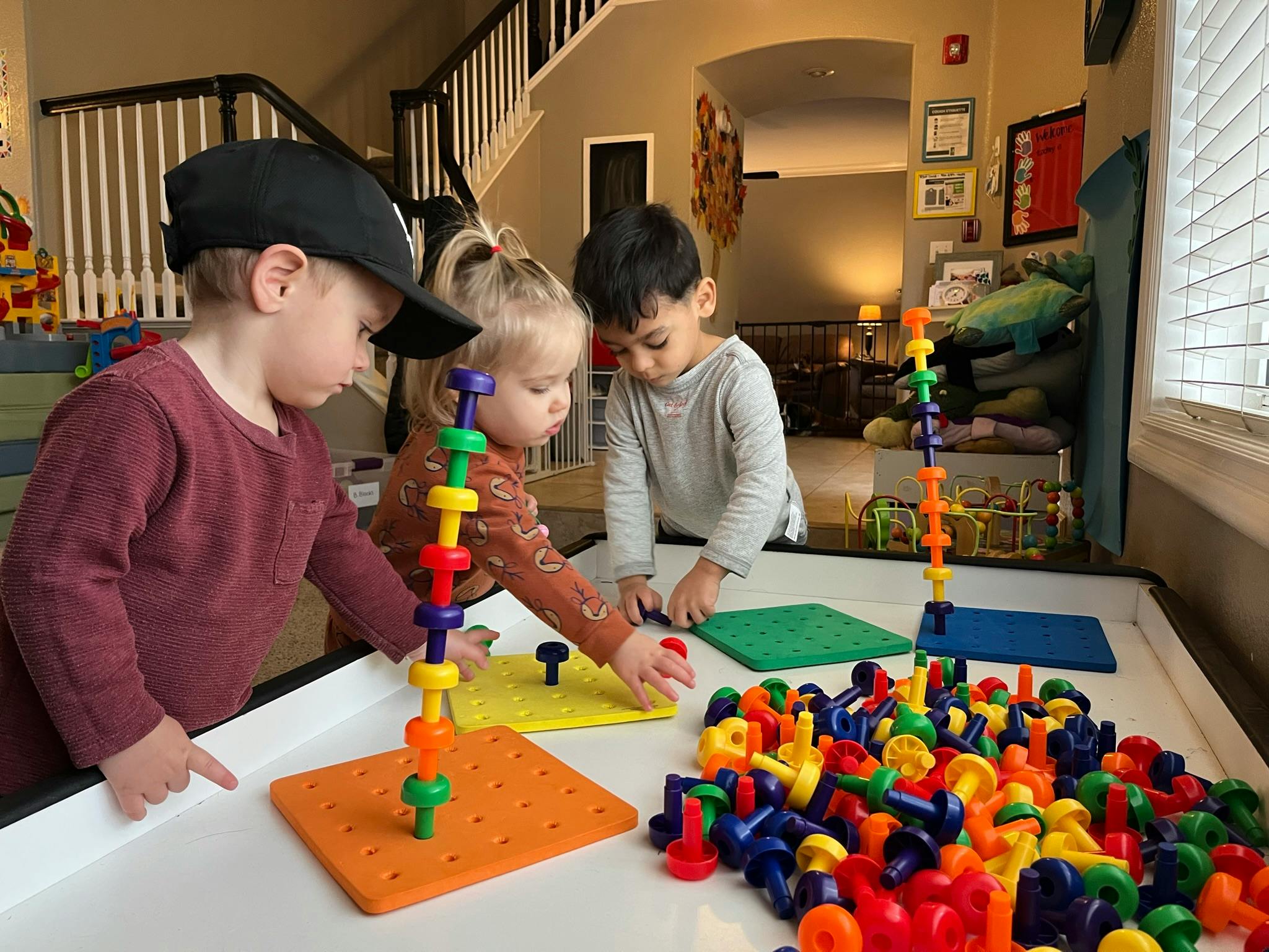 Three children playing with colorful building toys at a table