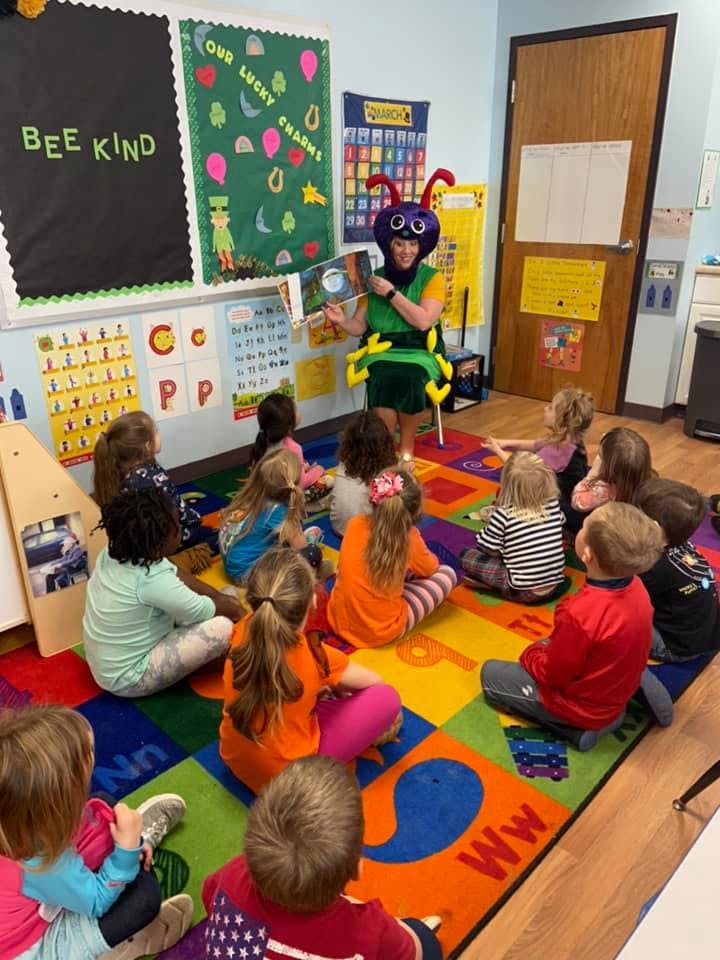 Person in costume reading a book to children in a classroom