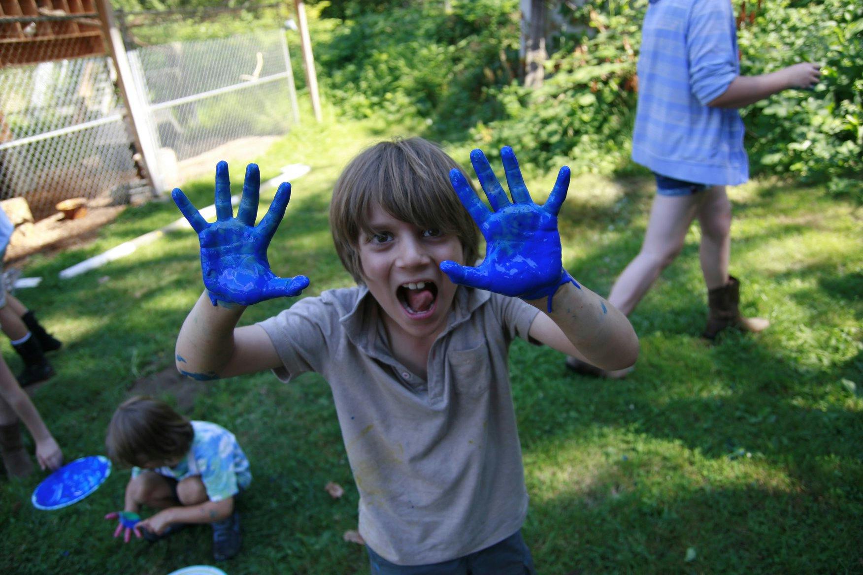 Child with blue paint on hands