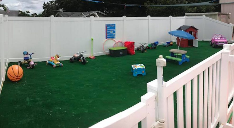 Outdoor play area with artificial turf, toys, and a small playhouse