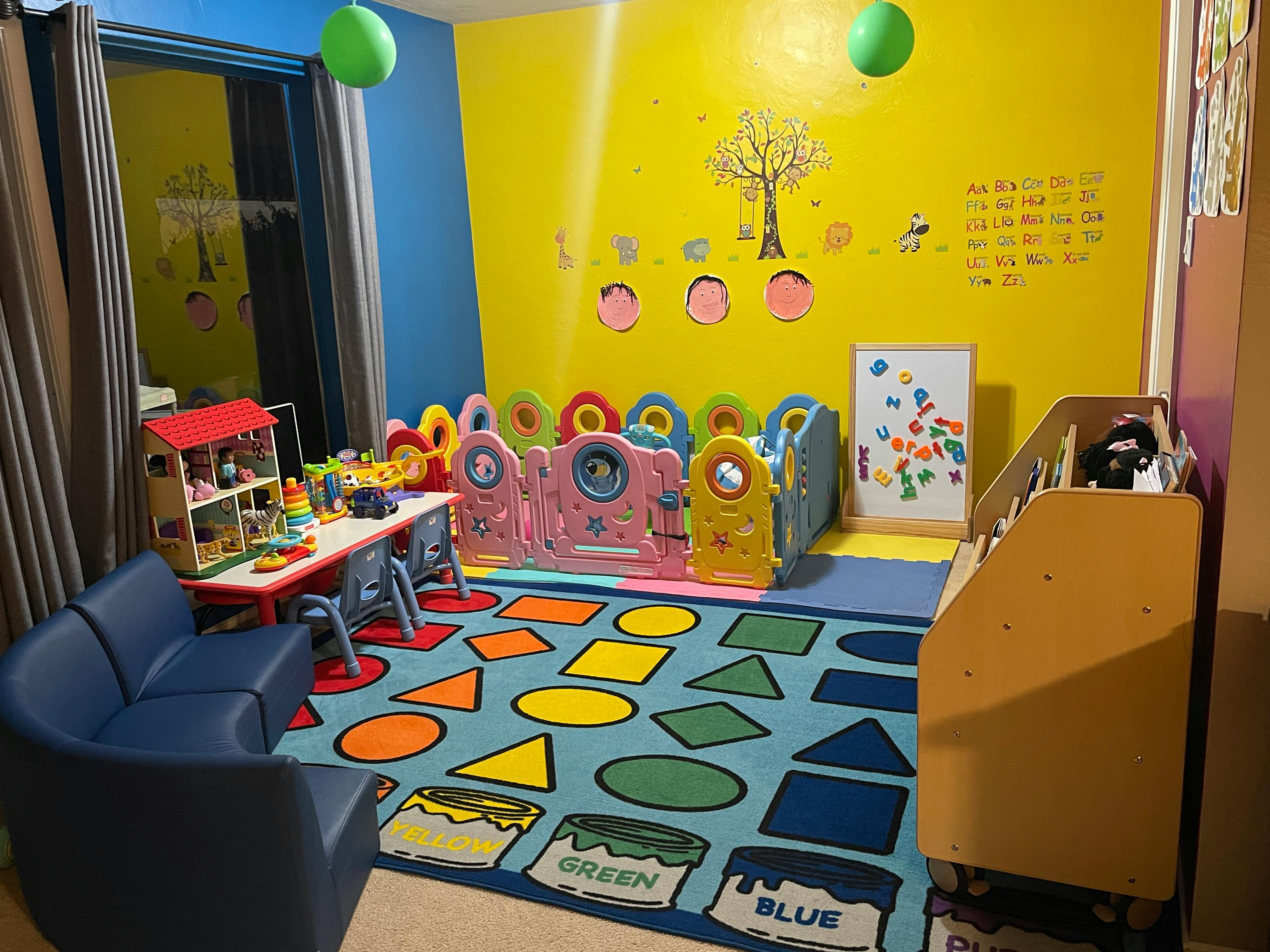 Playroom with a colorful rug, small table and chairs, and playpen