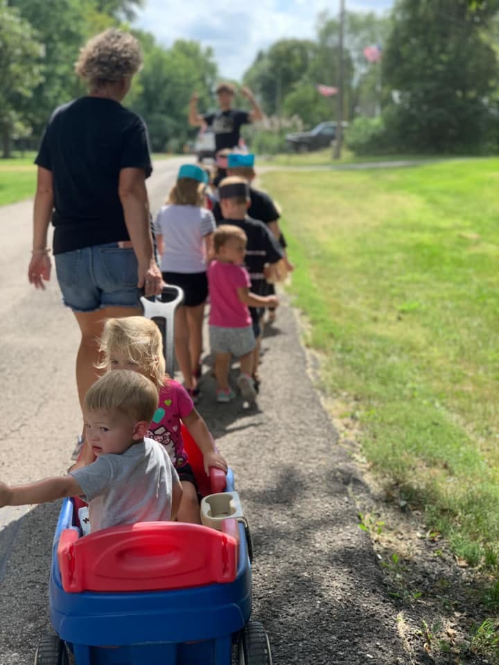 Person pulling a wagon with children, other children walking behind