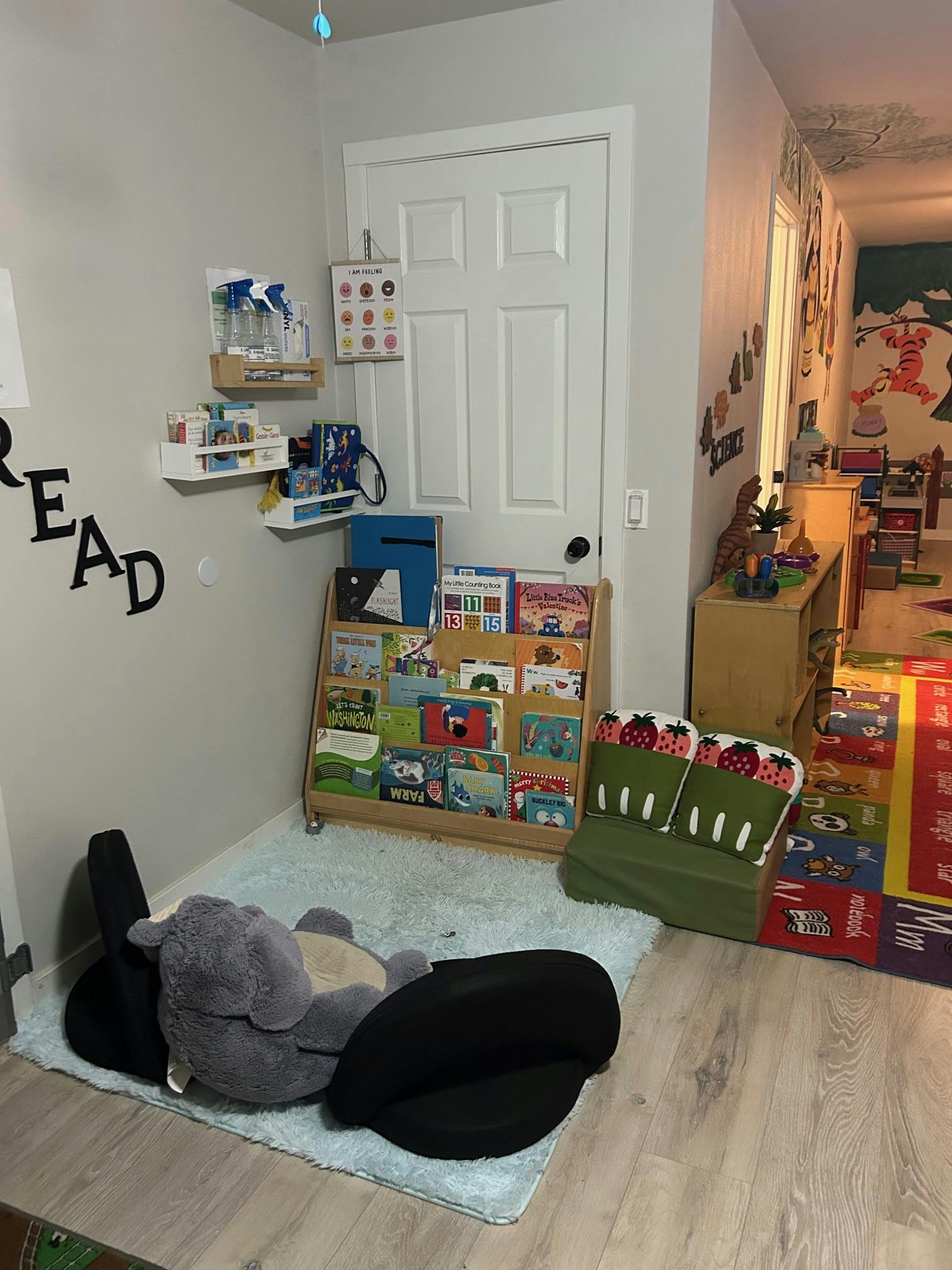 Children's room with a book display, green couch, and stuffed animal on a rug