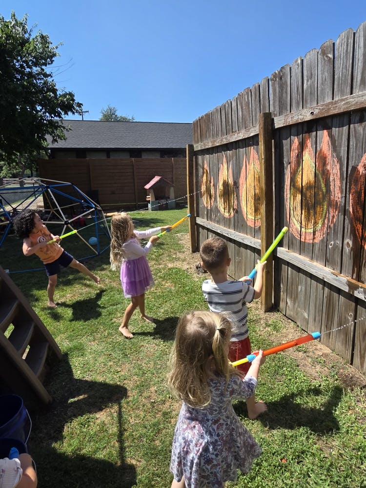 Children playing with water guns in a grassy yard